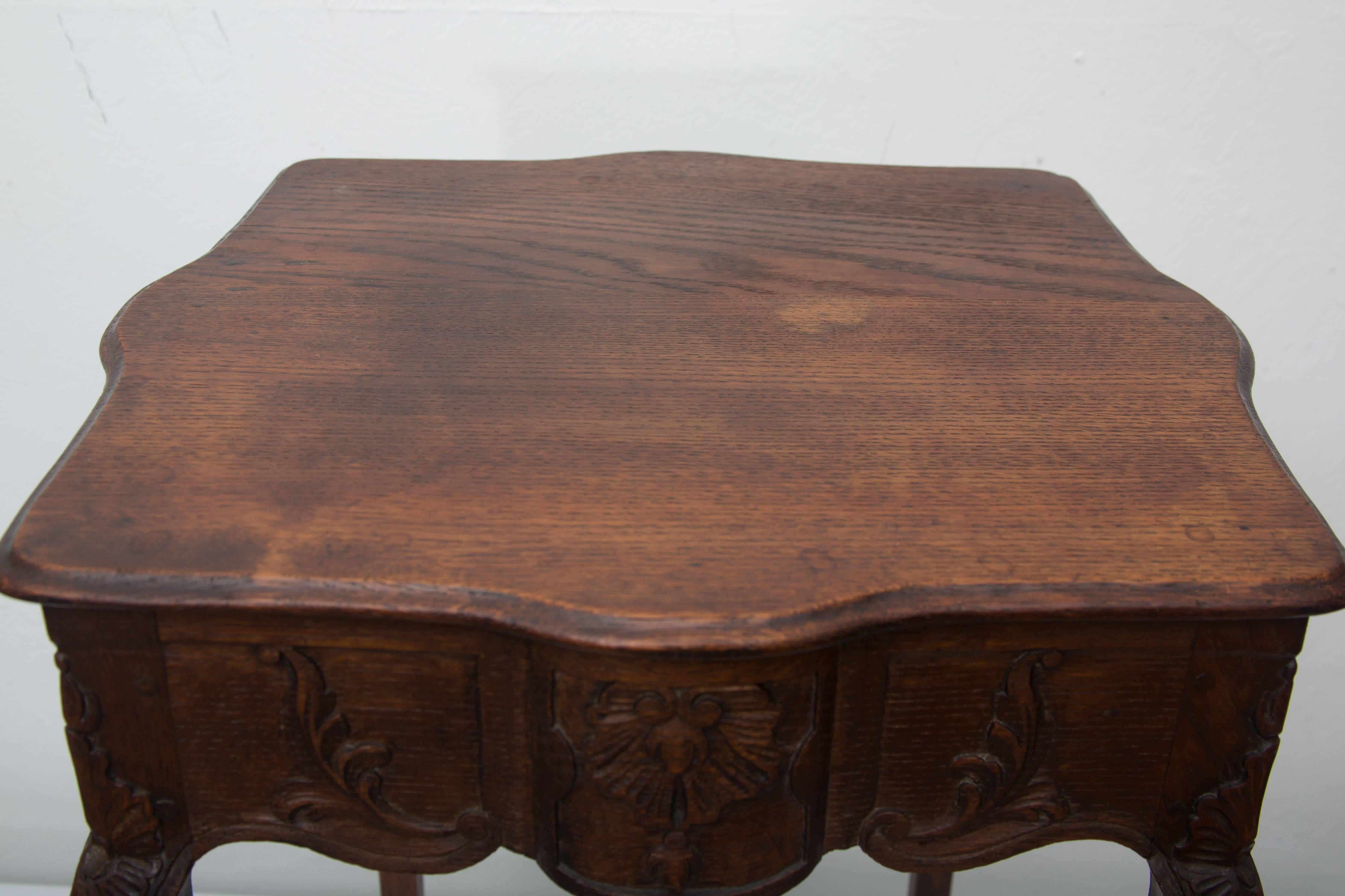 This small French dark oak and hand-carved side table is a perfect accent for an old world interior. It has a carved scalloped frieze and raised on delicate legs ending in hoof feet. Late 19th century.