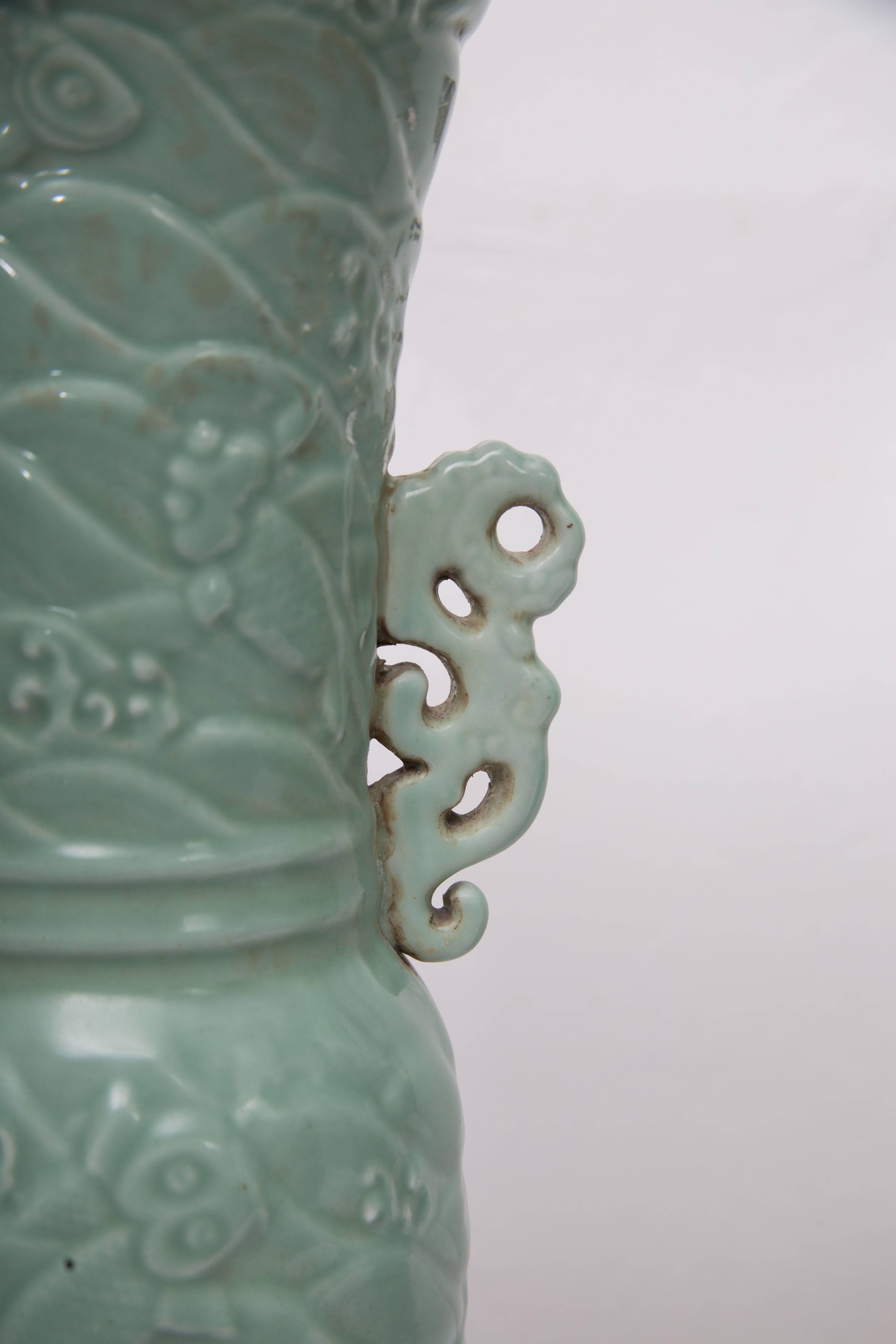 This is a distinctive pair of Chinese celadon trumpet urns with an impressive overall relief. 20th century.