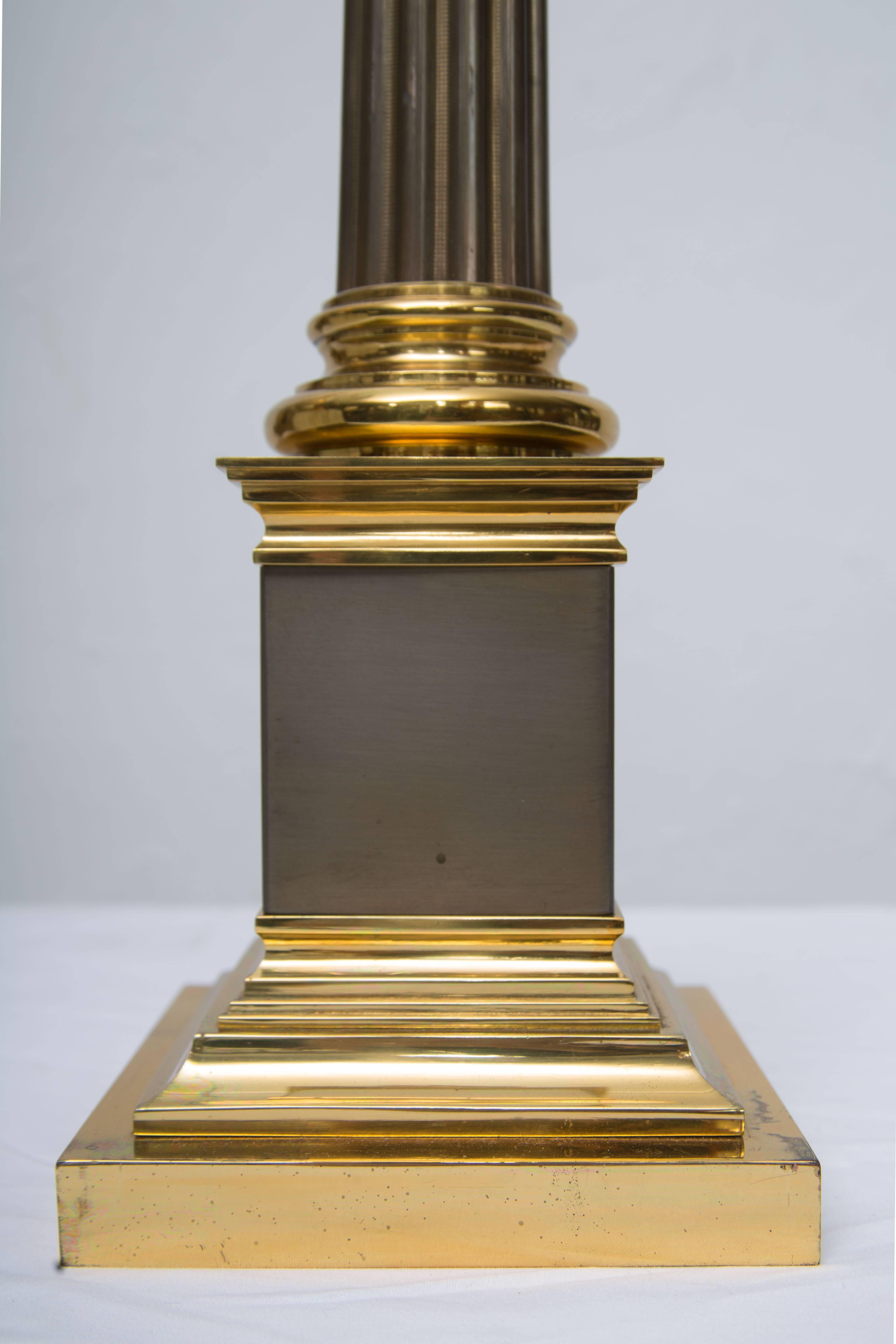 This classic pair of stately brass and steel architectural lamps are in the form of elegant fluted columns situated on a tall plinth and two-tier graduated base, circa 20th century.