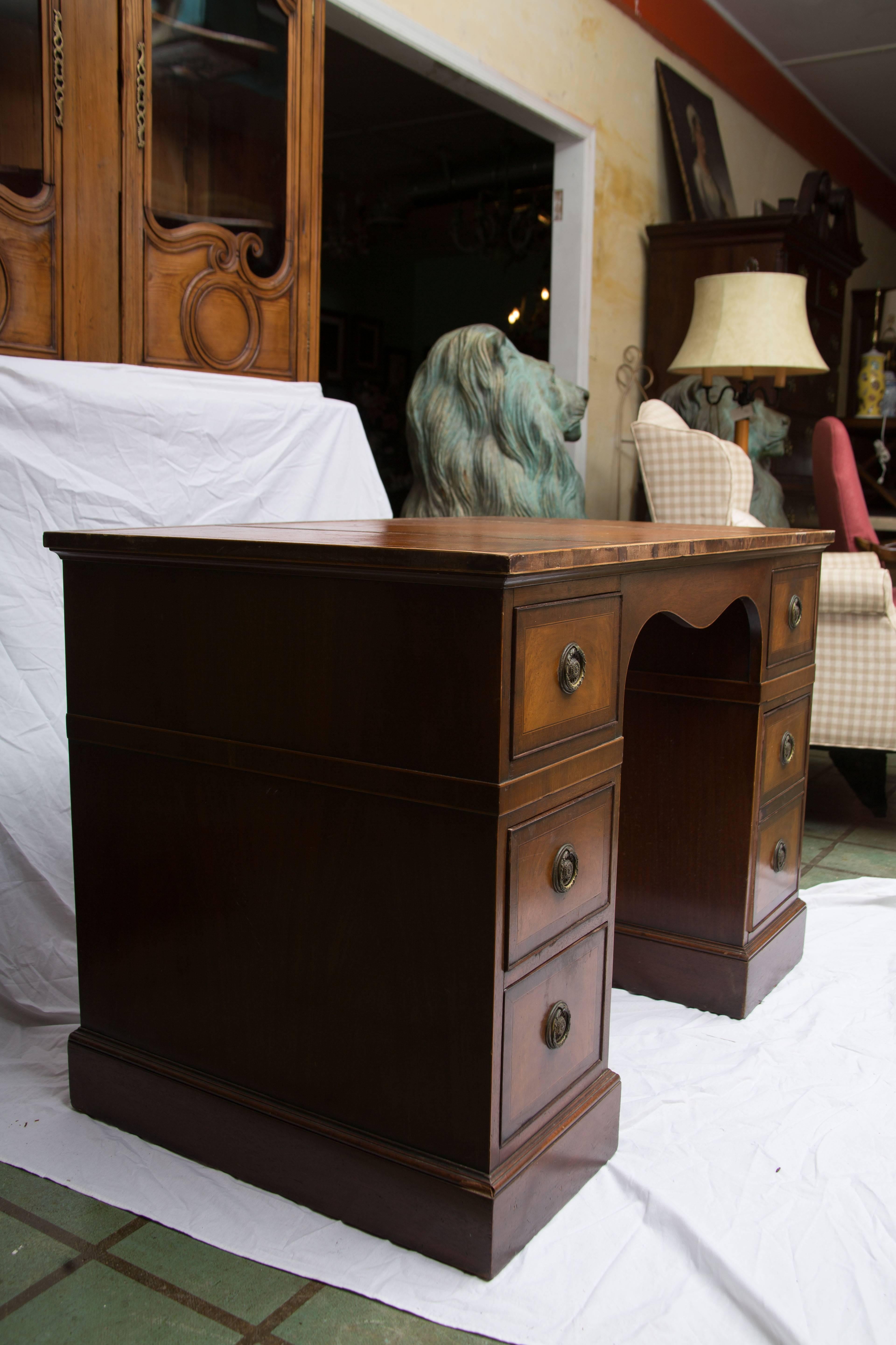 This late 19th century English pedestal desk offers a graceful element to a traditional and Classic interior. It's soft and mellow patina adds to its comfortable appeal. The leather top is raised by two pedestal sets of drawers raised on a plinth