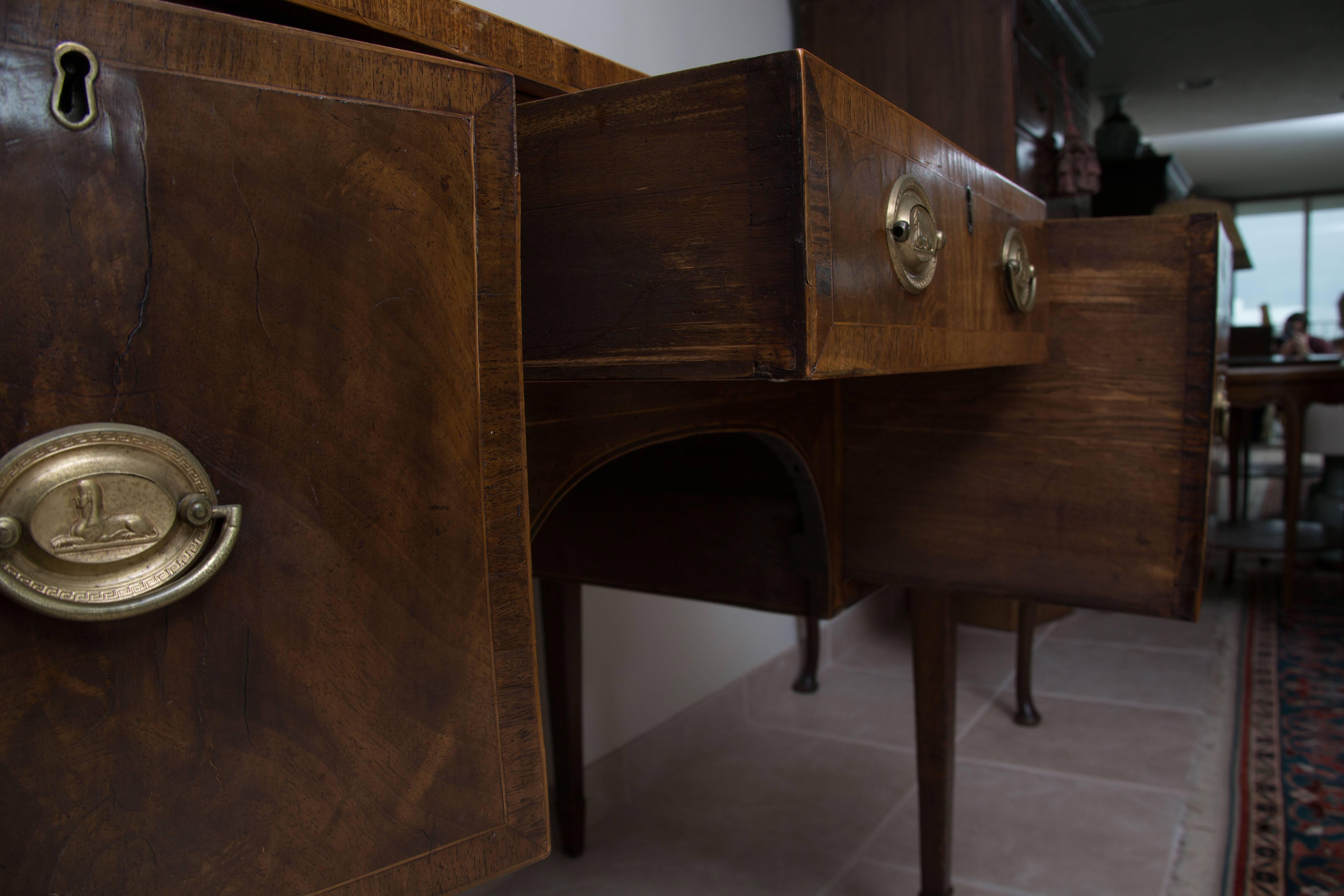 This lovely mellow George III mahogany sideboard has a plank top with straight edge over a central drawer flanked by two cupboard door supported by straight tapered legs with satinwood stringing throughout, circa 1815.