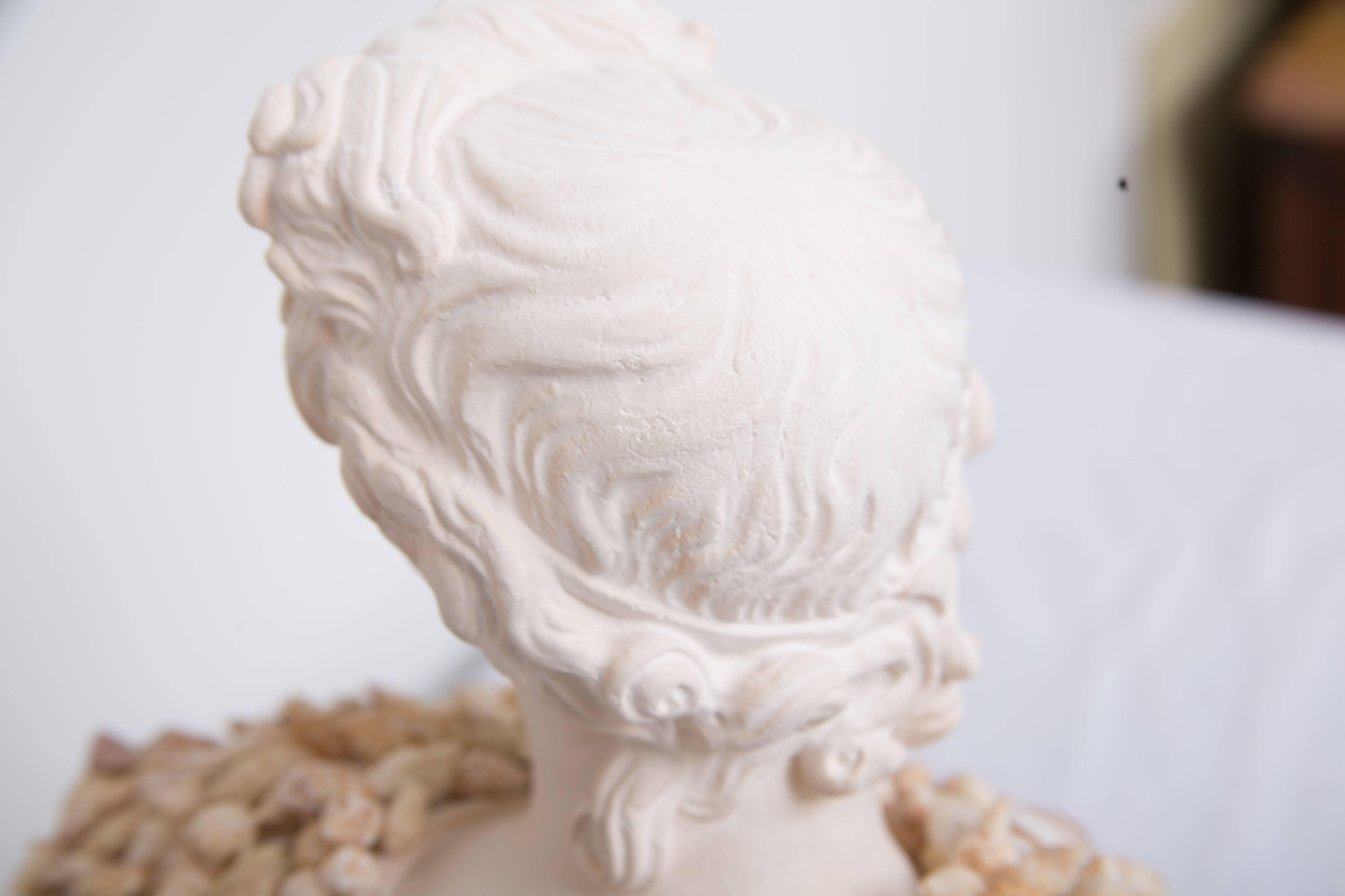 This composition bust of a classical figure has been enhanced by the modern application of shells, circa 21st century.