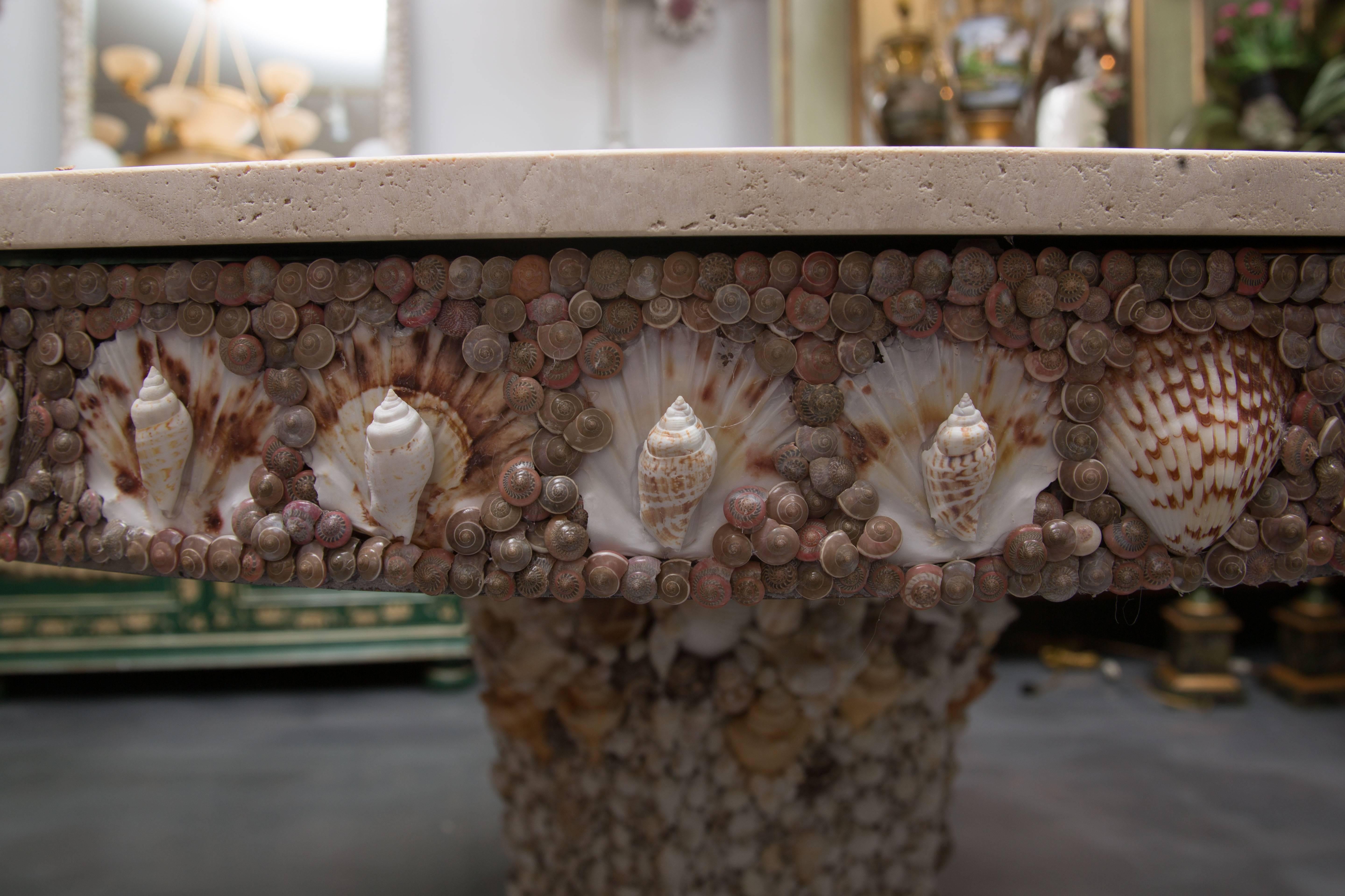 This magnificent centre table is encrusted with a variety of sea shells, offering a stunning alternative to a conventional centre table. The natural unfinished travertine top beautifully complements the natural shell Formations, circa 20th century.