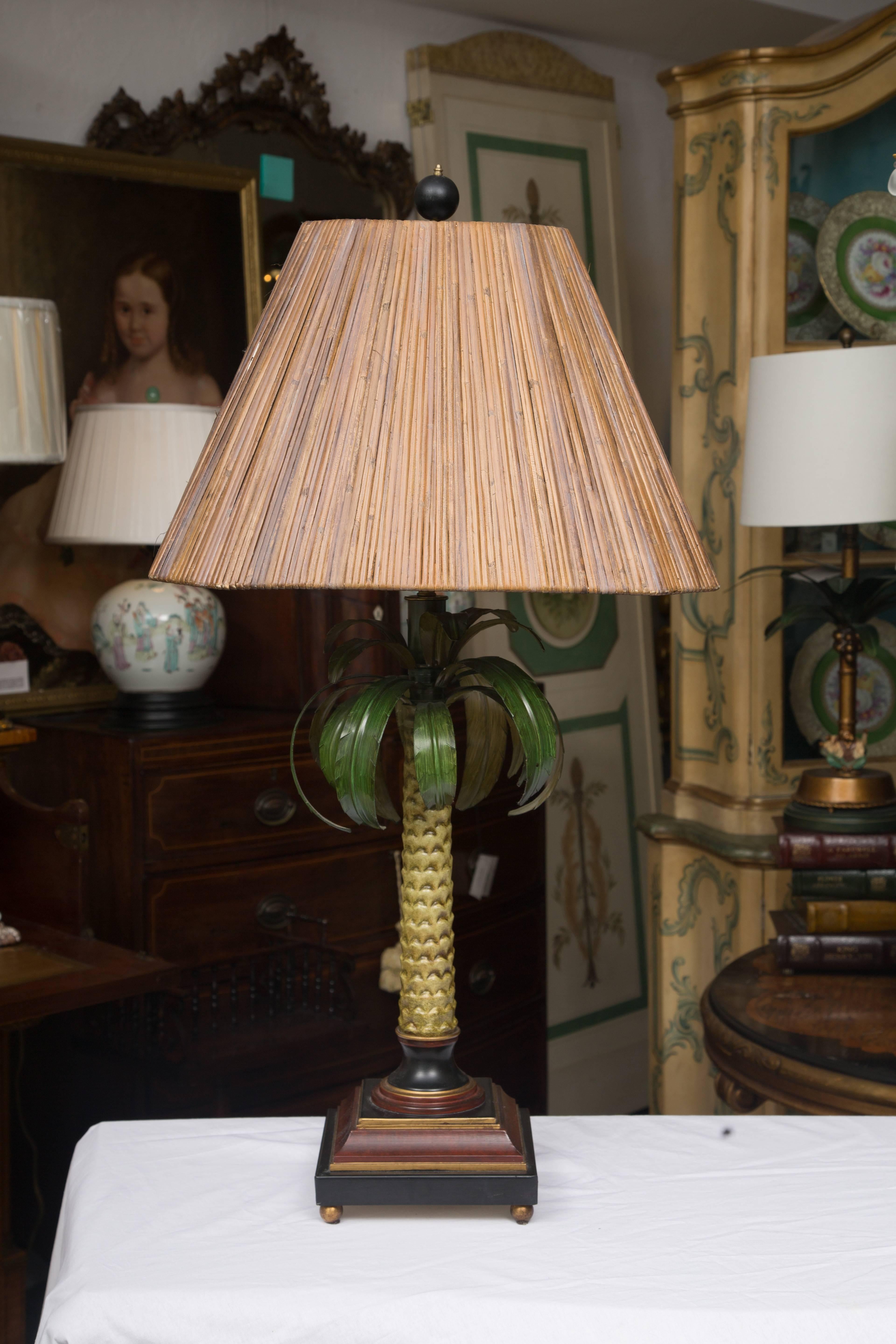 This is a very decorative pair of polychromed metal lamps in the form of dessert palm trees topped with graceful flowing fronds and situated on double ogee plinth bases with brass ball finials at each corner, 20th century.