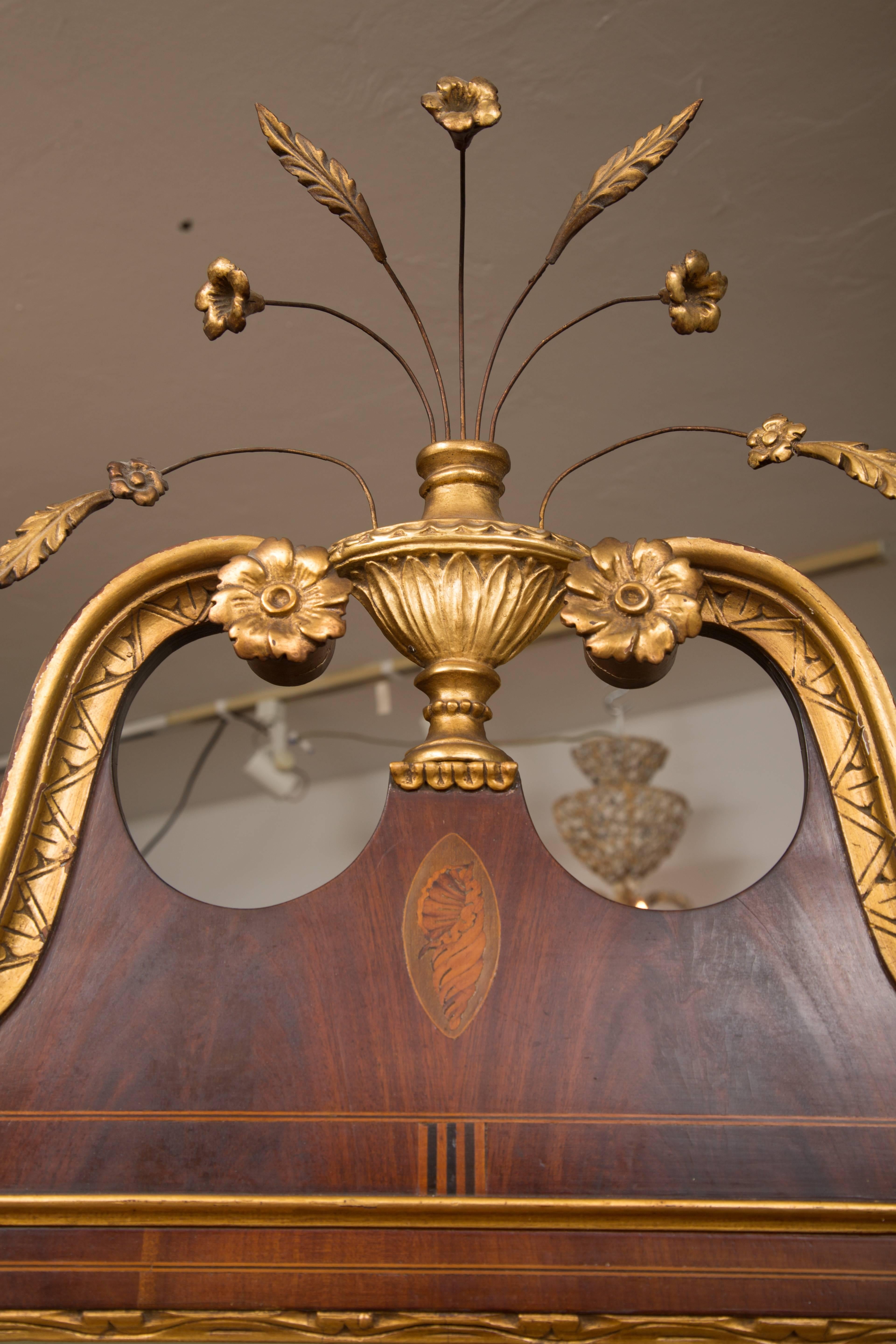 This is a Classic example of an American Federal style mahogany mirror with a prominent, yet graceful, swan neck pediment centered by a flowering urn above a églomisé panel over a rectangular mirror plate. The plate mirror is flanked by trailing
