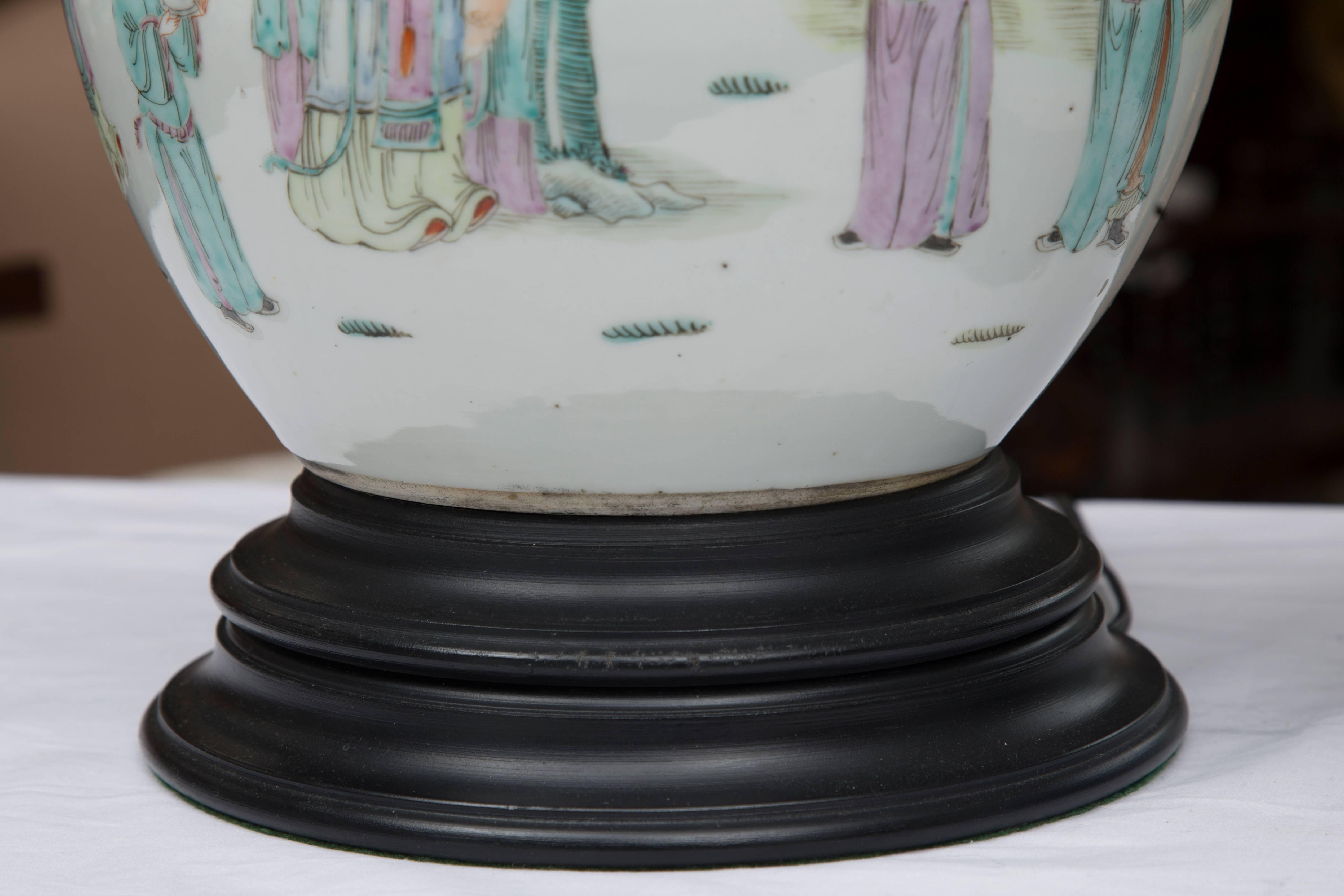 This is a good pair of antique melon jars with facing Asian figures in a naturalistic setting delicately painted in quiet pastel colors on a neutral background and situated on circular wooden bases, circa 19th century.