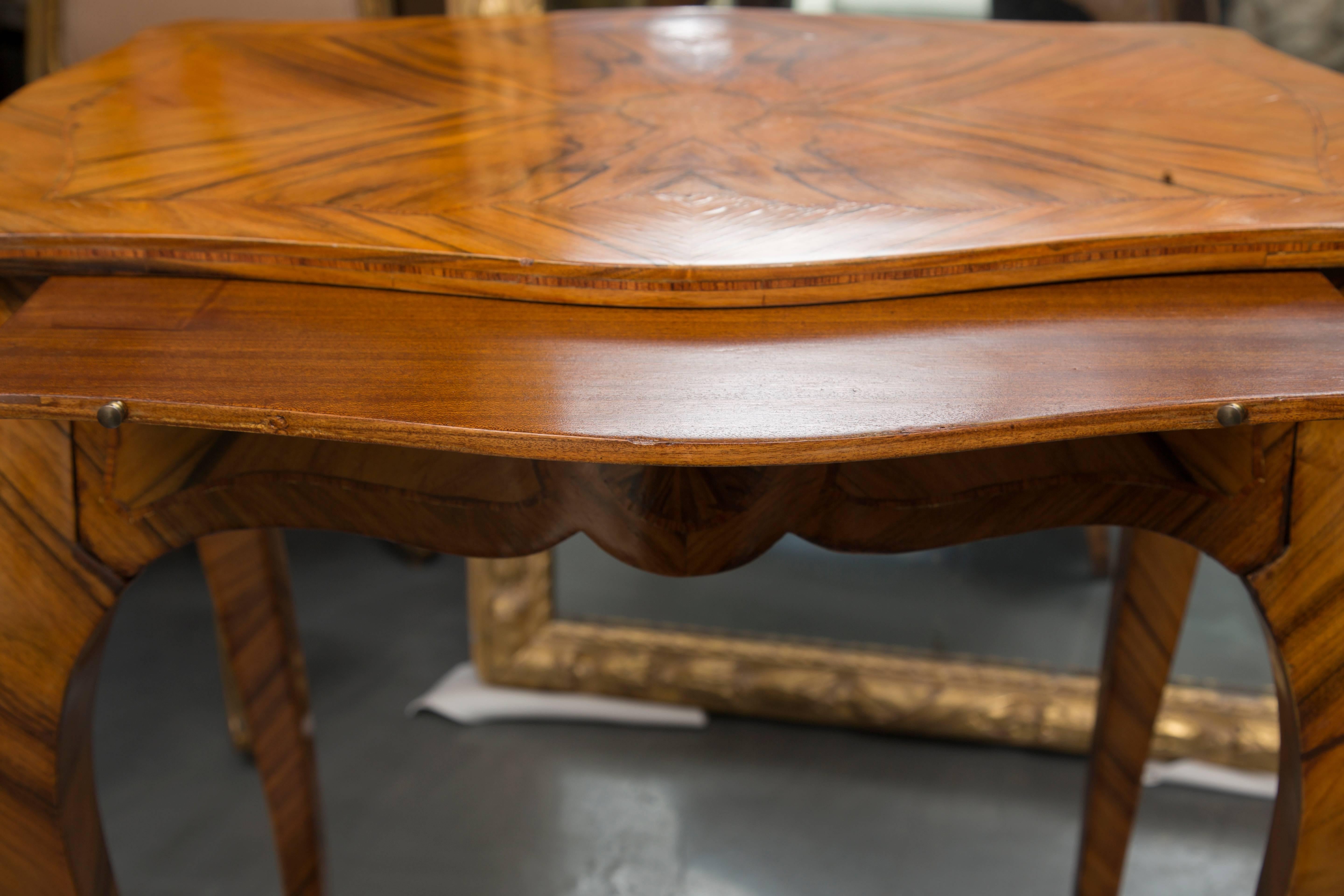 This Louis XV style kingwood table has a cartouche shaped top with mirrored veneers over a brush slide and frieze drawer, supported by graceful slender cabriole legs joined by a plateau stretcher replicating mirrored veneers of the top, circa 19th