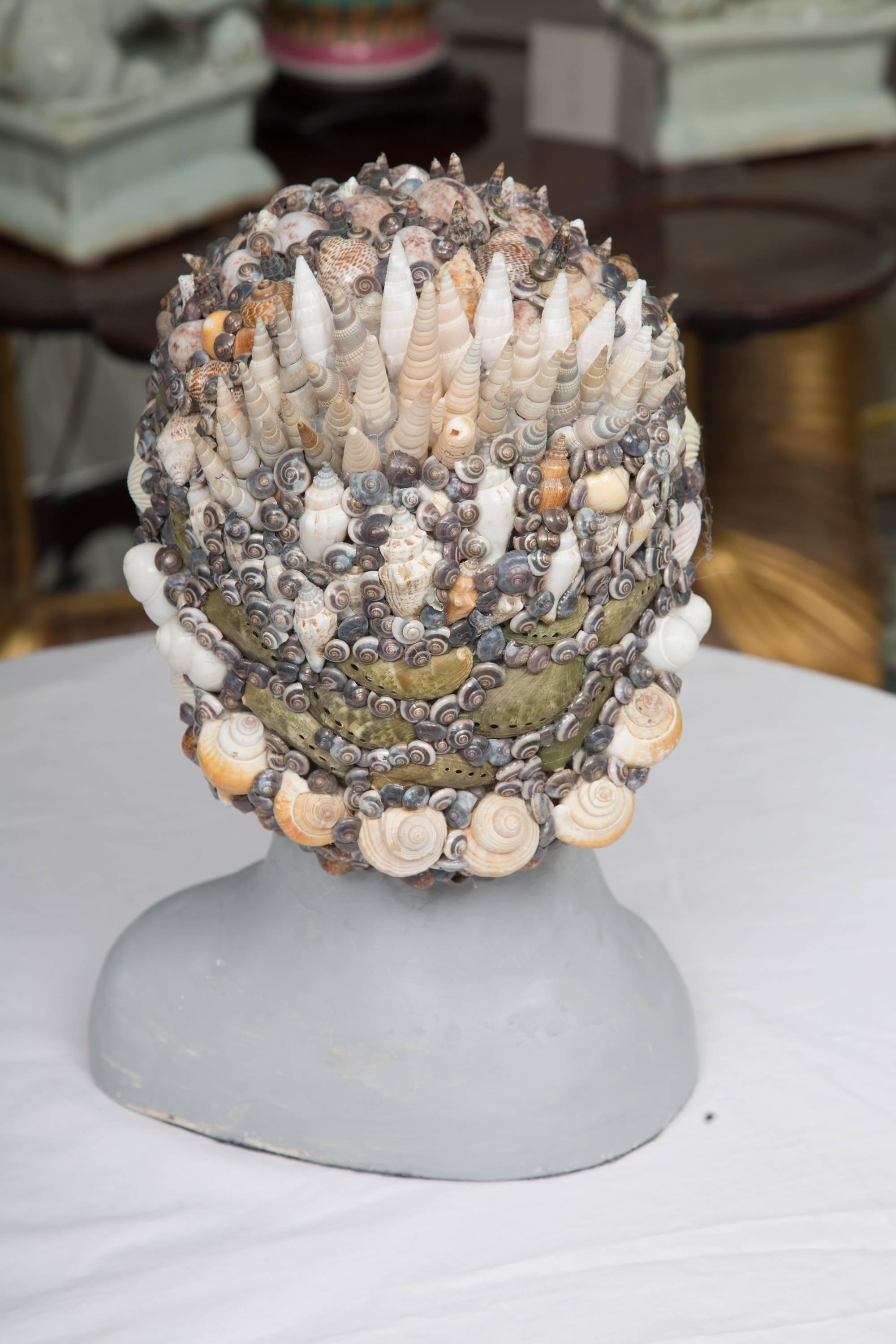This grey composition bust has a classic, yet contemporary presence and is artistically enhanced by the application of a shell headdress, 20th century.