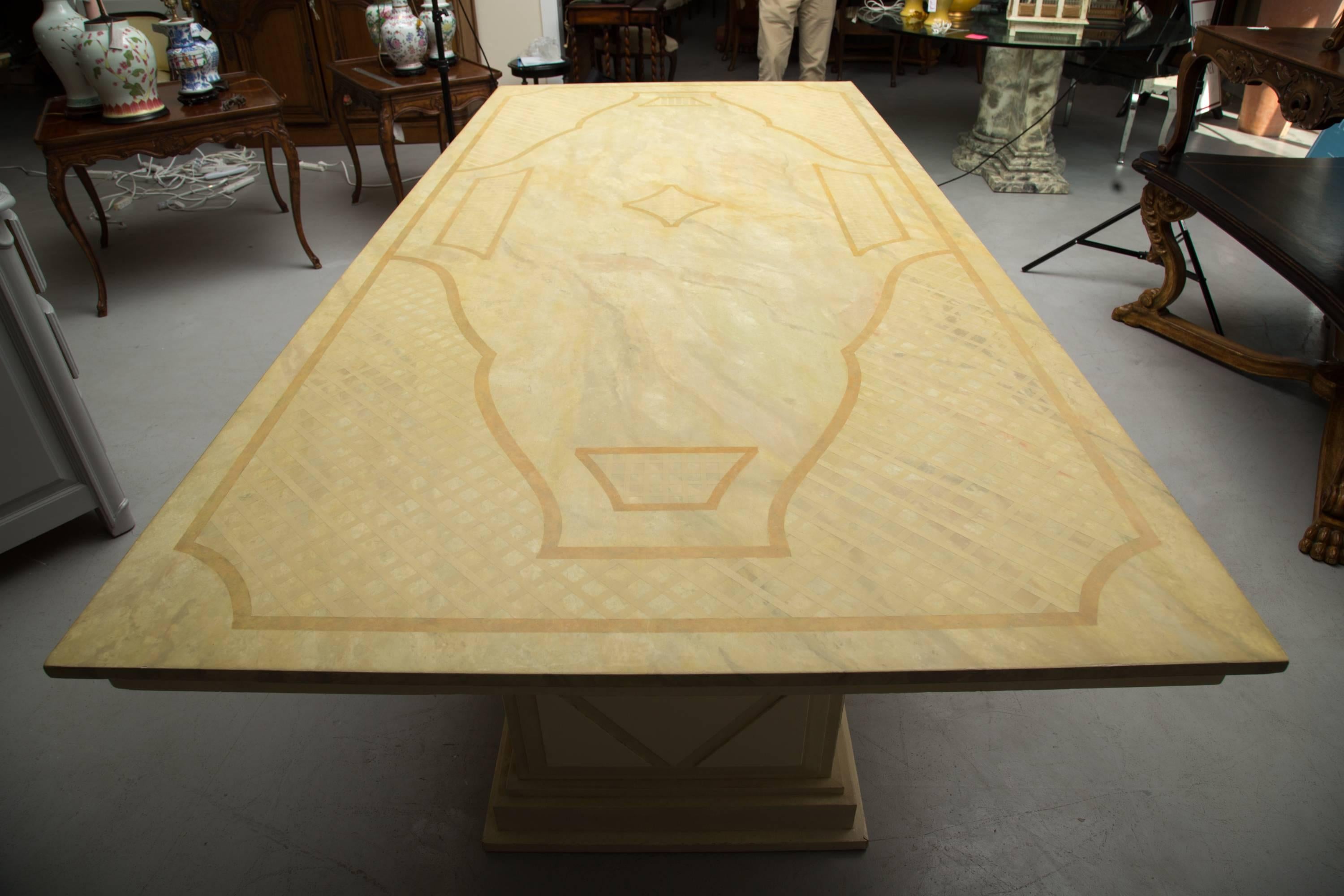 This is an elegant Italian dining table. The top is custom painted with a faux Jerusalem limestone finish, and embellished with a painted decorative ornamentation. The case piece supported by two plinths with geometric architectural moldings, 20th
