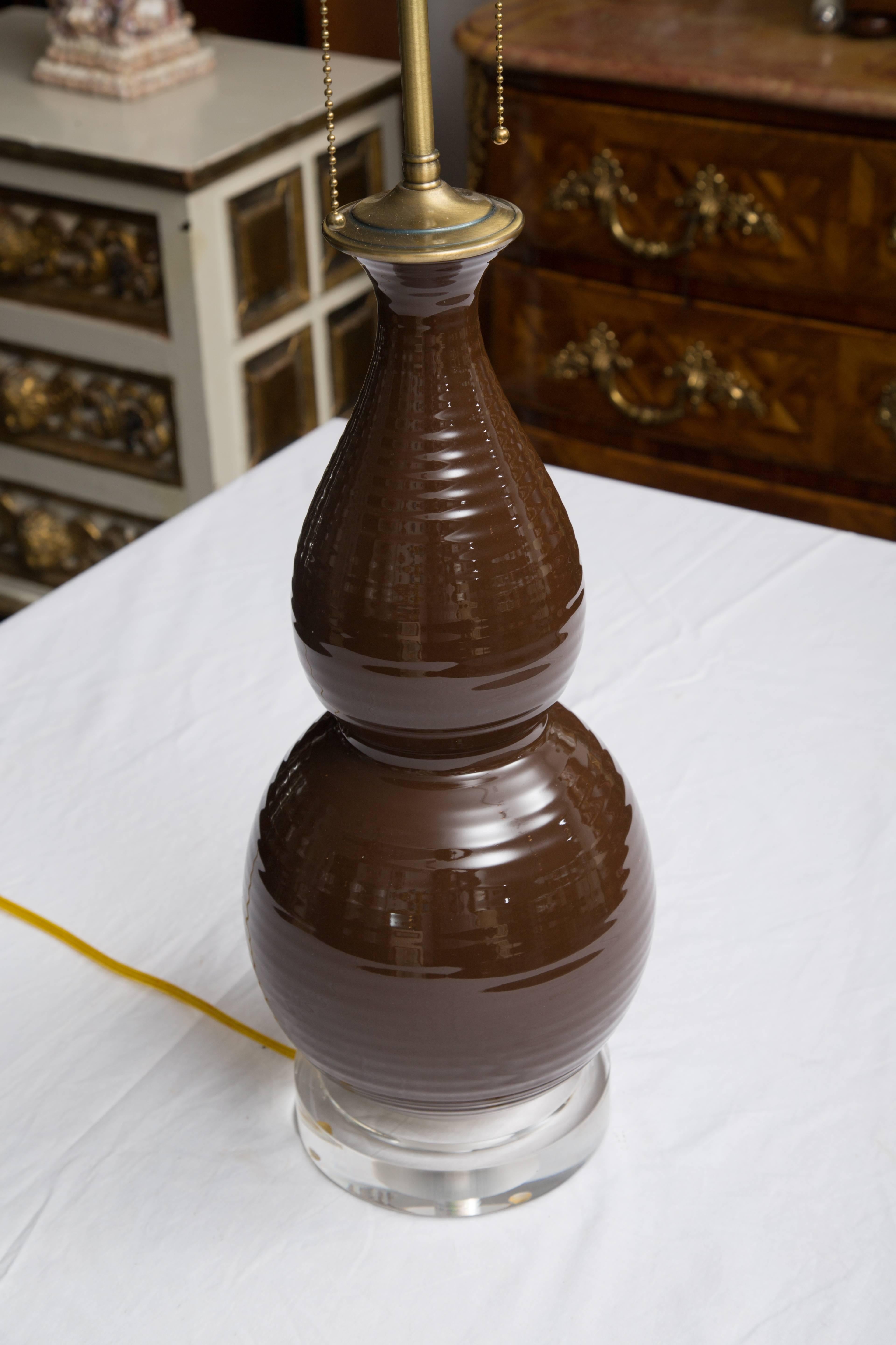 This is a pair of decorative chocolate brown double gourd table lamps with a 'ribbed' design on the gourd, The lamps are situated on circular plexiglass bases. 20th century.
