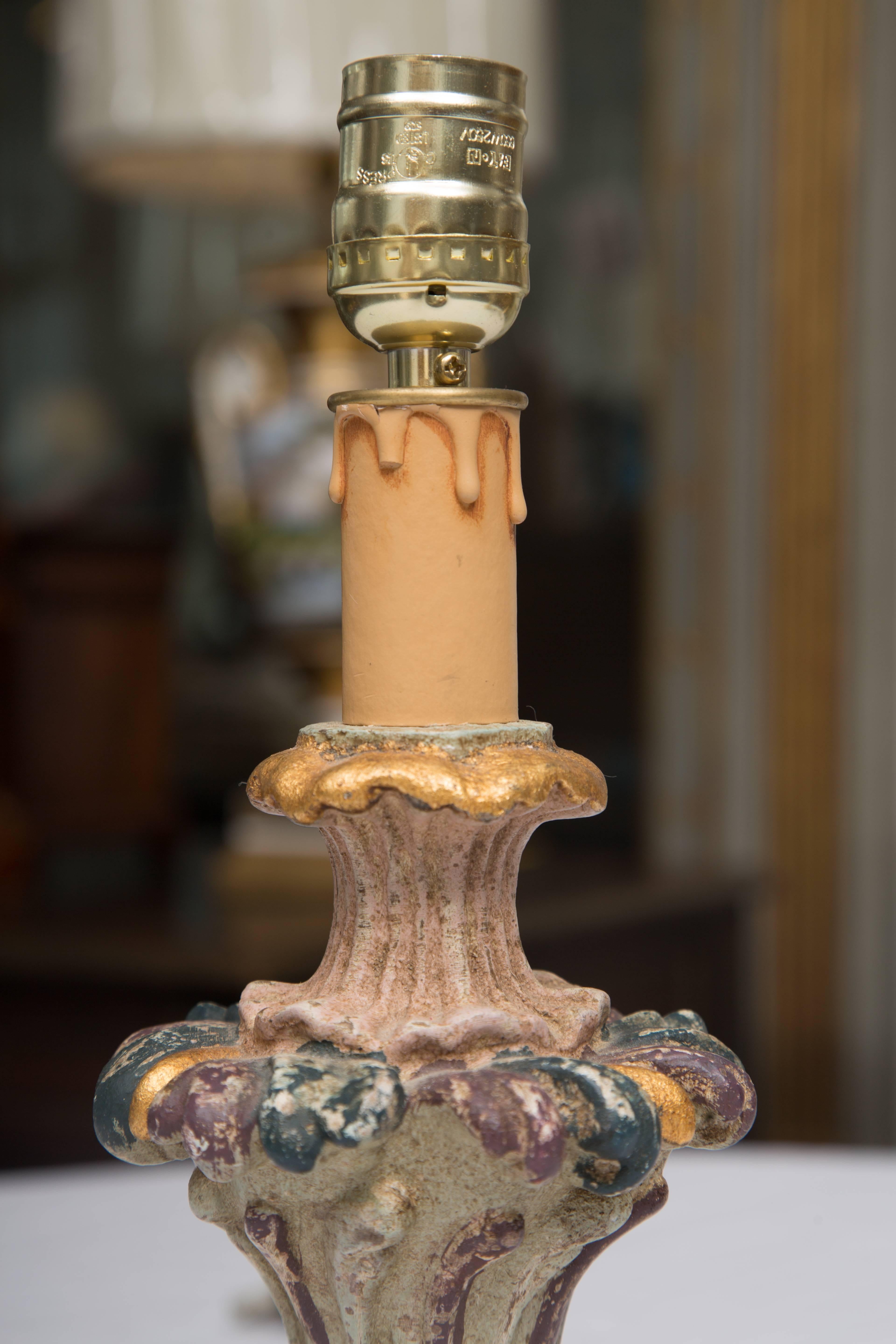 These small Italian candleholders in the form of urns are hand-carved and painted with soft and delicate colors with parcel-gilt, and situated on circular bases. They have been converted to small lamps.