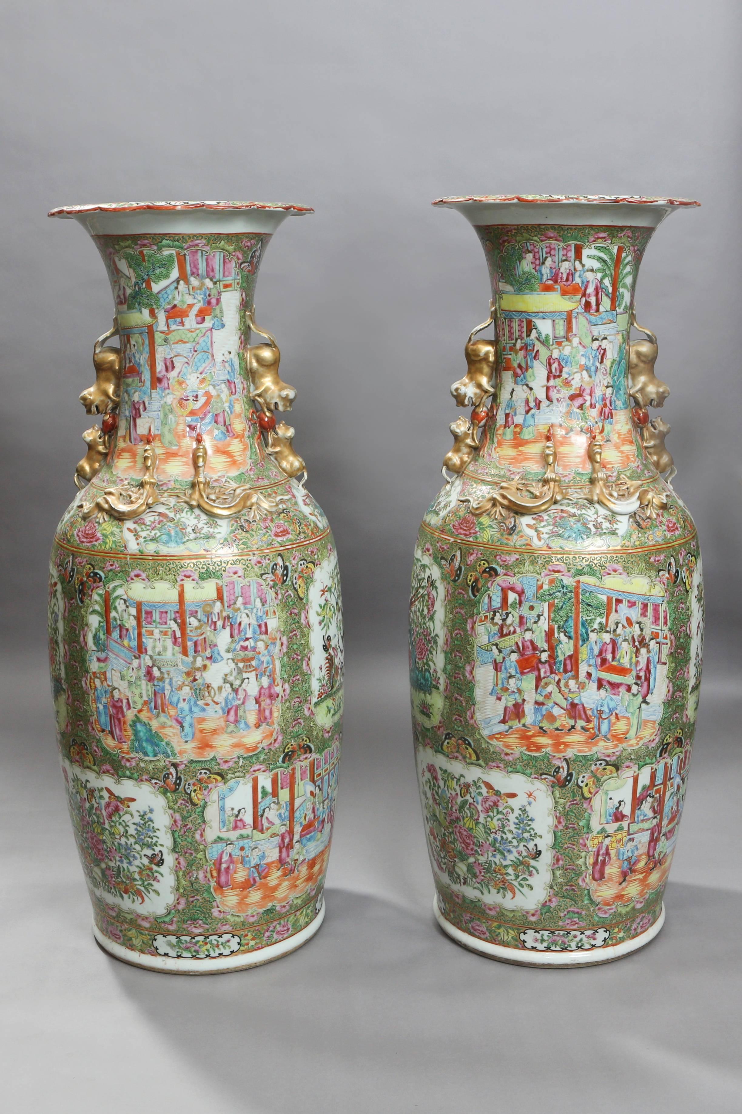 These large 19th century Canton export vases are enamelled all-over with variant panels of: court scenes, flowers, insects, and precious objects. The handles are each decorated with a lion and pup, playing with a ball. Protruding outwards from the