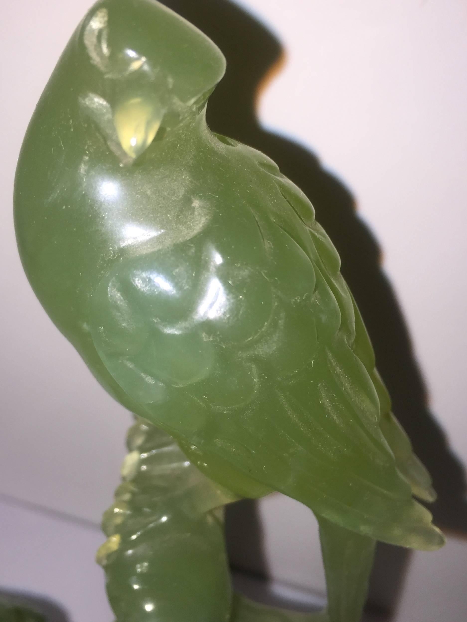 The carved green serpentine group depicts two birds perched upon branches of a tree stub. One sits sideways at the end of the stub looking straight on, as the other smaller bird facing the viewer turns its head up at the larger bird from the lower