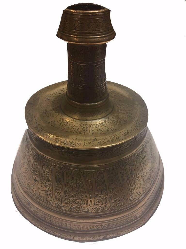 A Mamluk silver-inlaid brass Candlestick 
Egypt or Syria, late 13th-early 14th century
of truncated conical form with flattened drip tray, the tapering neck terminating in a tapering raised band, engraved with a band of thuluth inscription