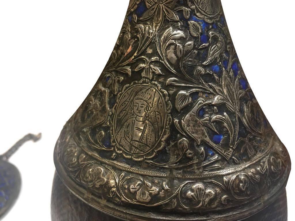 19th century, a Qajar silver enamel hookah with a leather base. Rising from a wide base, tapering to a long, slender neck and flared rim. Profusely decorated with engraved floral motifs

- Measures: 21 cm x 13 cm
- 17 cm x 9 cm.