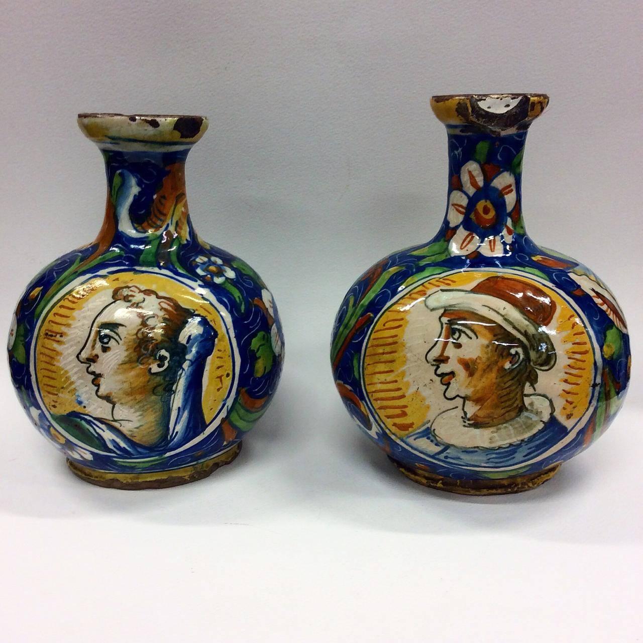 Each of the vases in a matching shape of a globular body with a neck featuring a gently flaring rim. They are painted with a blue ground featuring circular medallions on either side of the rounded body. One side of each vase features a painting of a