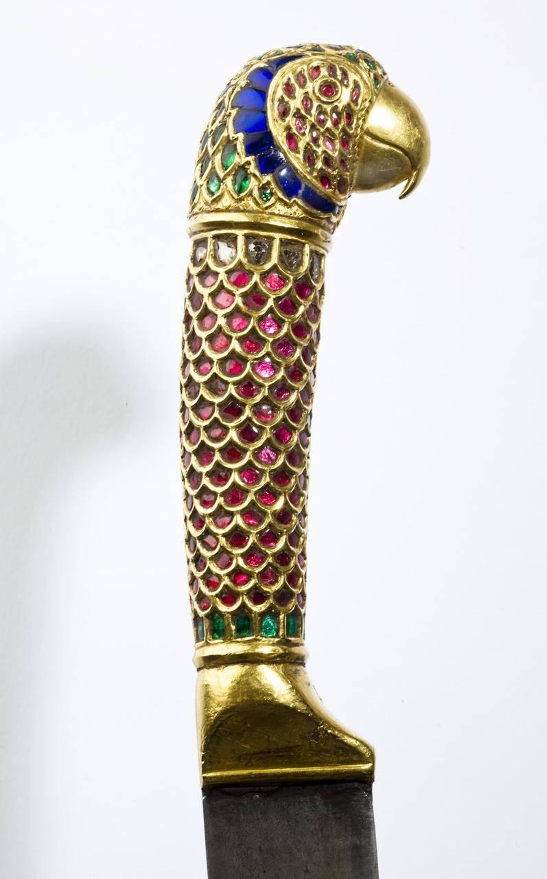 With finely watered steel straight blade with tapering point, the hilt of solid gold in the shape of a parrot, encrusted with rubies, sapphires, diamonds and emeralds.