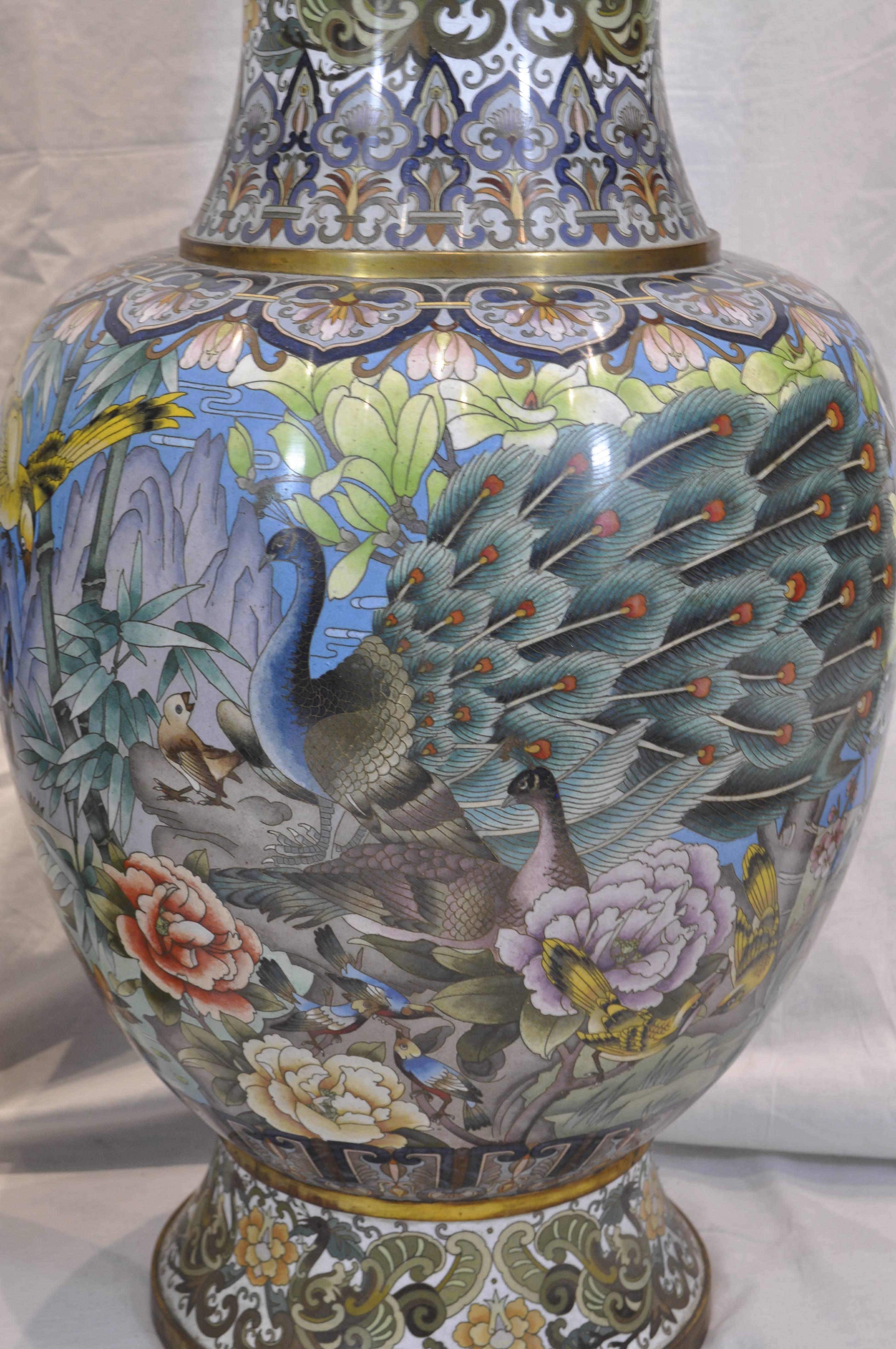 A pair of Chinese ormolu-mounted polychrome cloisonné vases decorated with a variety of birds including: roosters, peacocks, parrots, pigeons, doves and more. They also feature flowers and branches on the main body sections, whilst the neck and foot