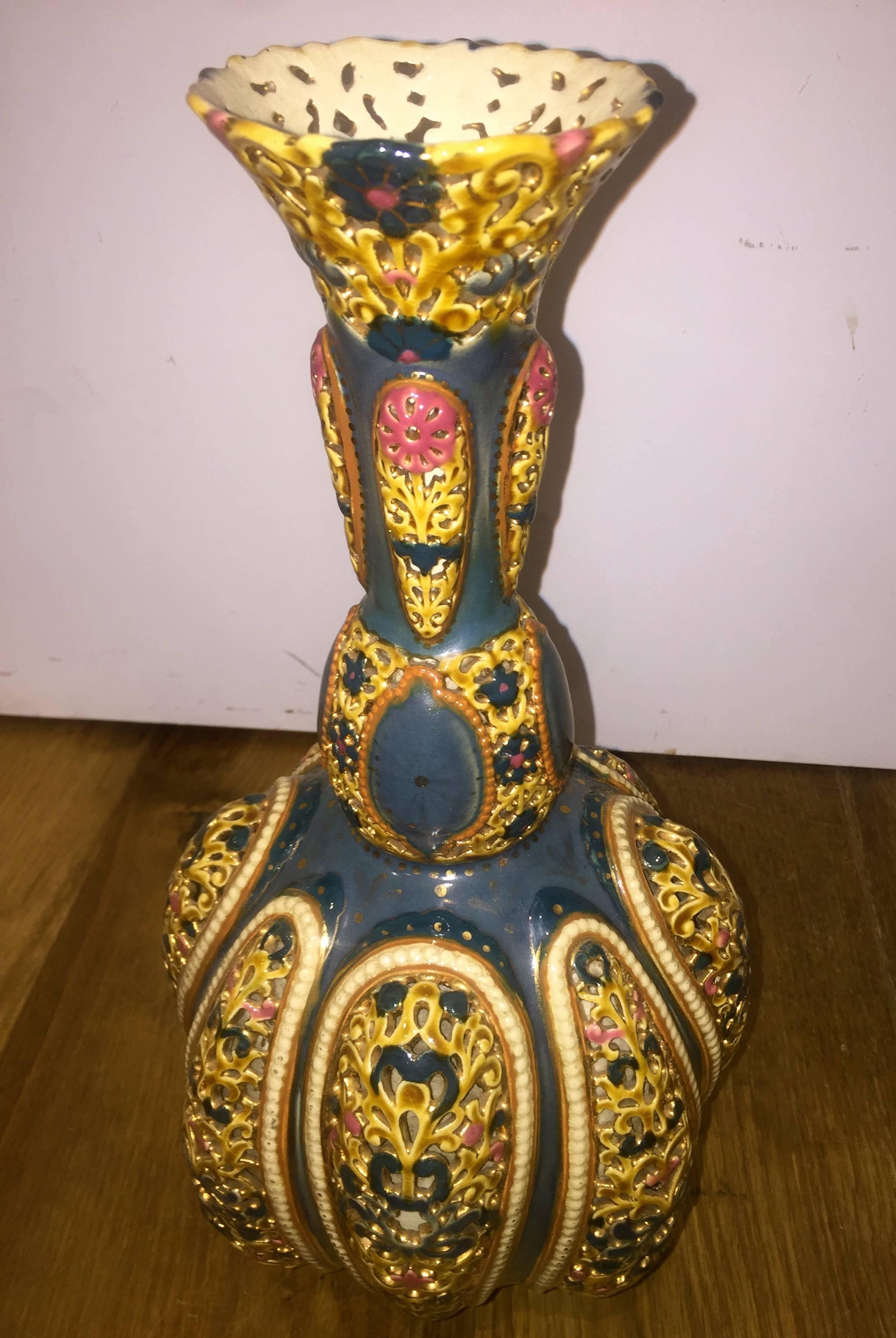 Of a Persian-style bottle-vase shape with 'pierced' or reticulated floral-motif portions on the flaring neck and the bulbous body. The body features alternating inverted rounded off teardrop shaped reticulated portions with a 'beaded' border. The