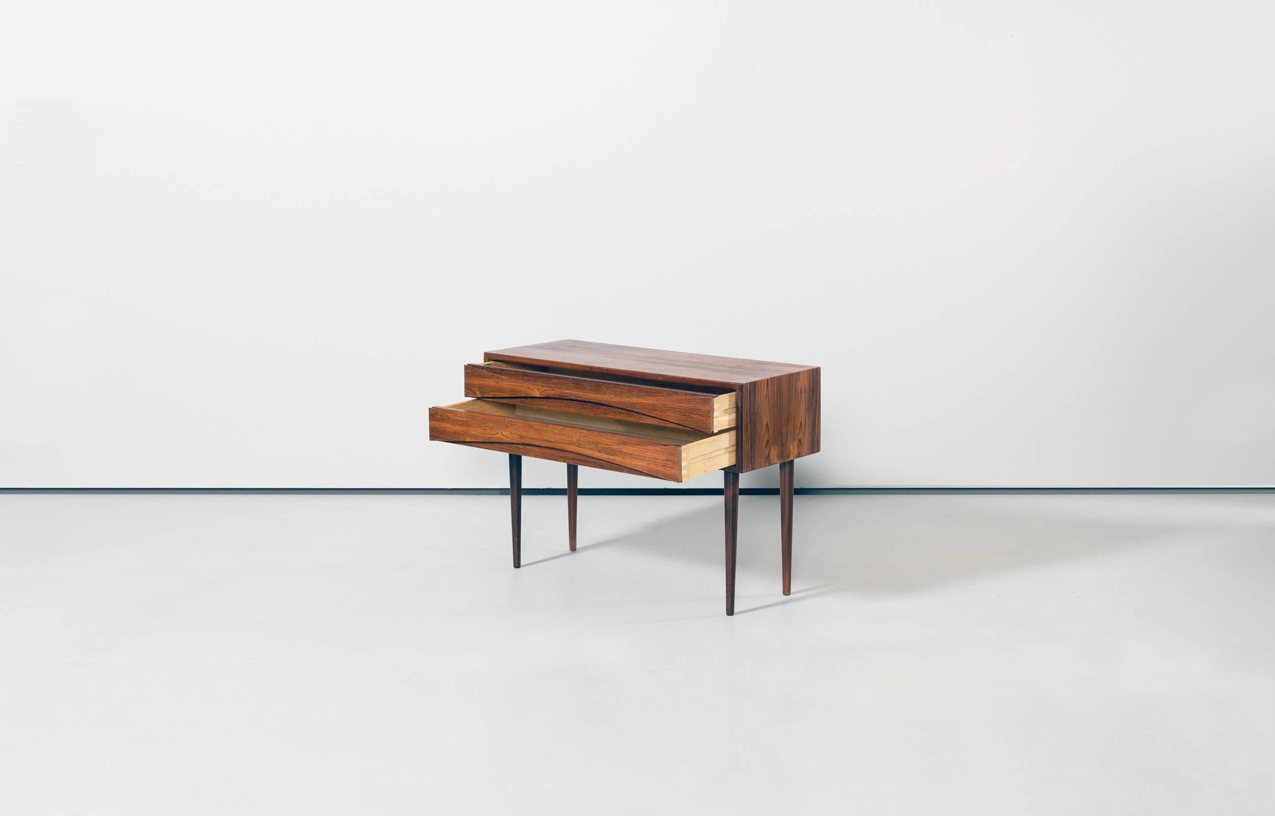 Rare chest of drawers designed by Arne Vodder and distributed by Sibast / NC Møbler, Odense. Highly structured wood grain. Chest made of veneer, legs of solid rosewood. A wonderful piece.

Perfect original condition with minor wear consistent with