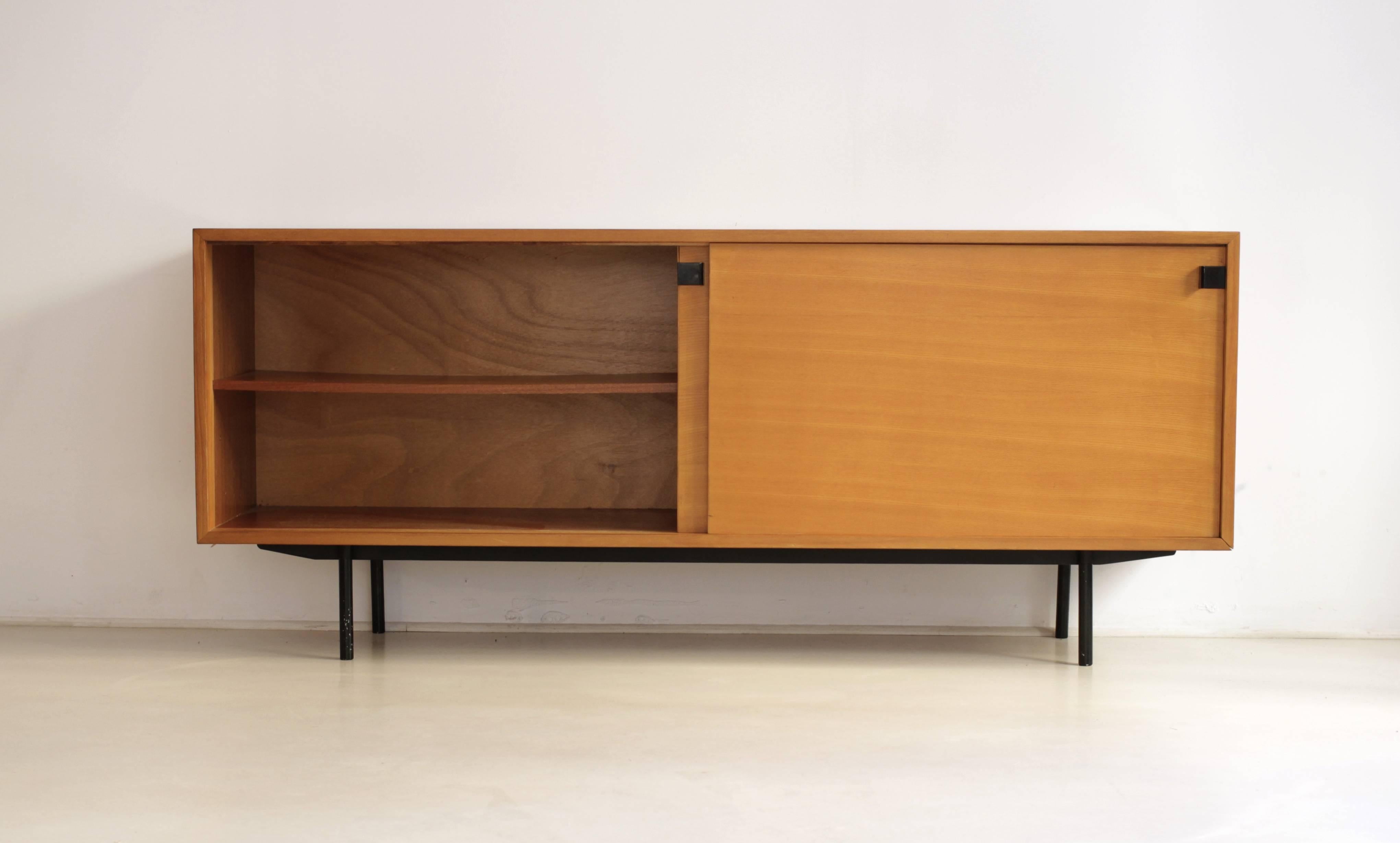 This Minimalist sideboard was designed by Alain Richard and manufactured by Meubles TV in France during the 1950s. It is made from elmwood veneer. The base is made of black lacquered metal.