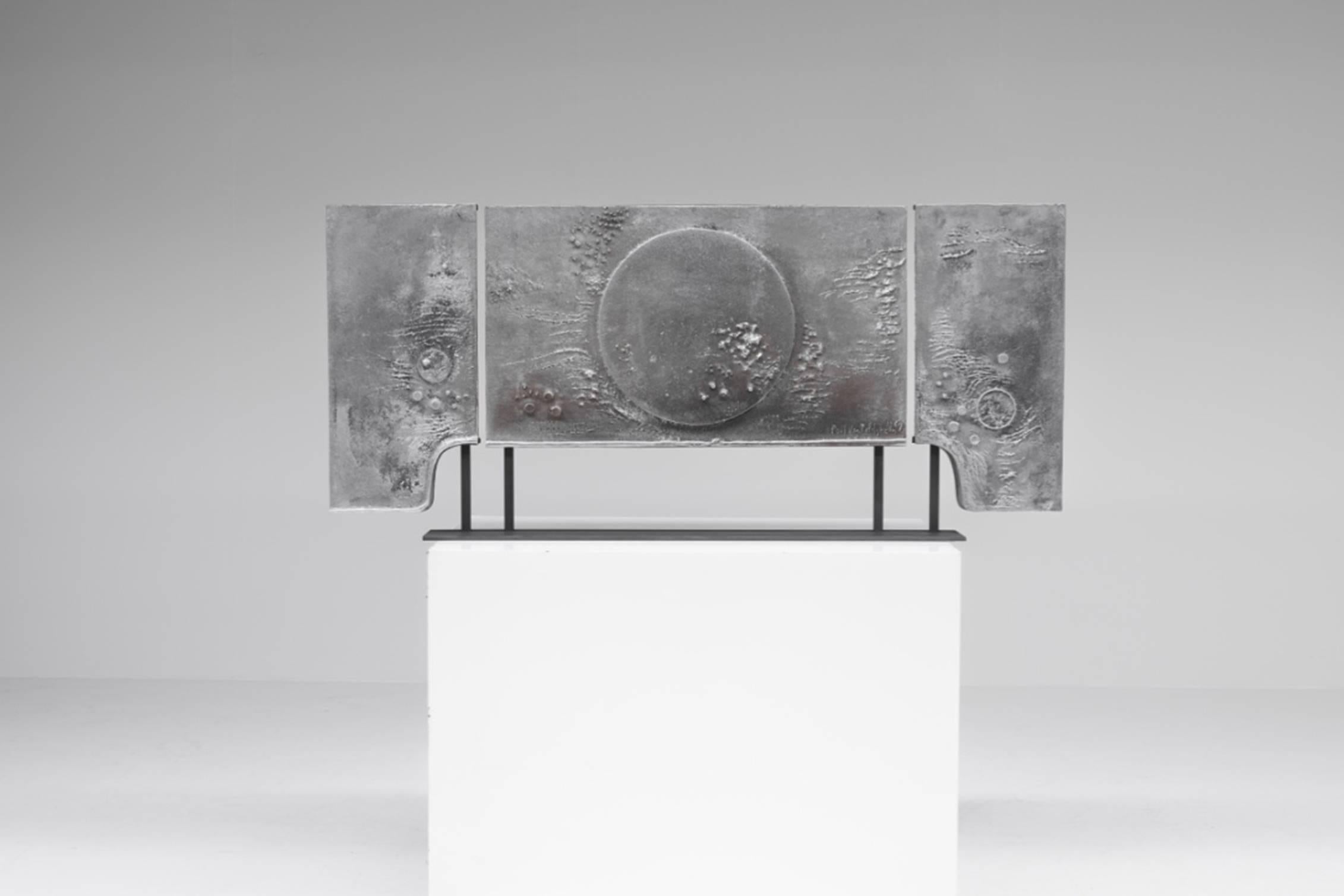 Cast aluminum mantelpiece triptych, mounted on a socle by artist Paul van Rafelghem, signed 1969, Courtois, Belgium.

An abstract, interstellar image is depicted in the casted relief. 

