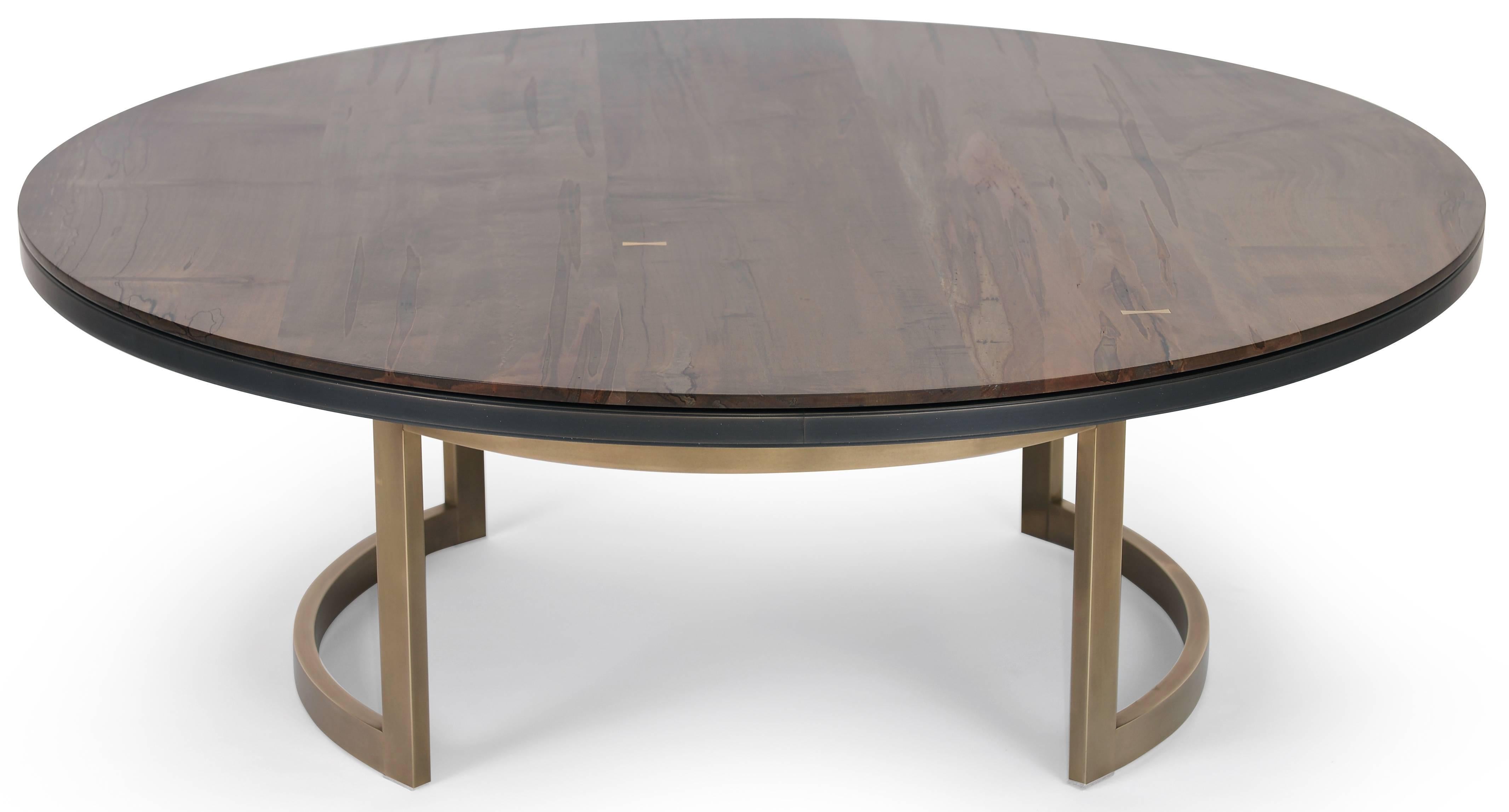 The luxurious Gotham coffee table features a two-tiered tabletop and an elegantly curved architectural bronze base. The top layer is handcrafted oxidized ambrosia maple bookmatched planks with bronze butterflies, and the bottom is blackened bronze