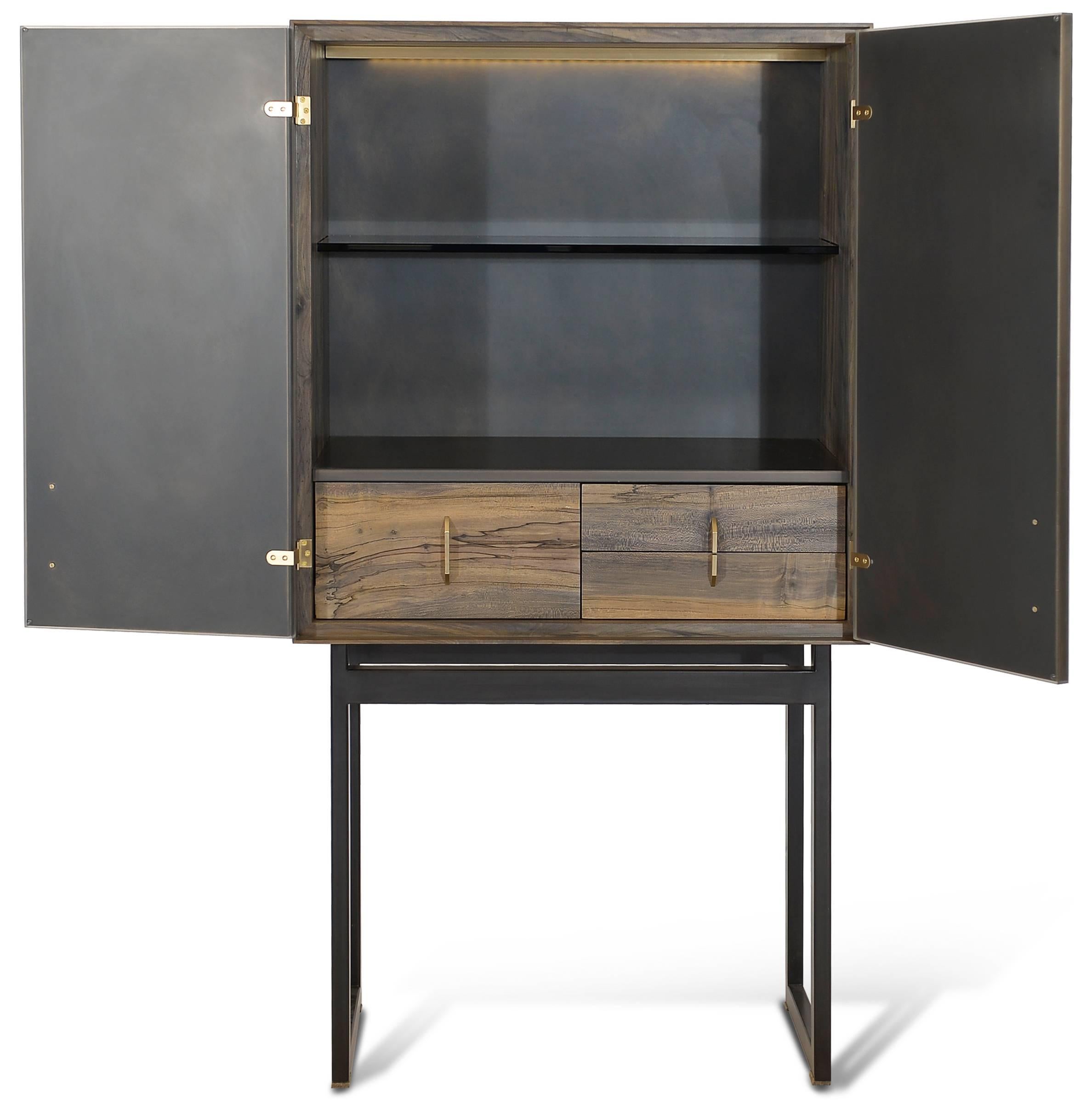 Included in the Gotham collection is this striking bar cabinet. Sitting on top of a modern blackened steel frame is an oxidized ambrosia maple cabinet with blackened bronze encased in resin doors and hand-sculpted bronze pulls. The interior features