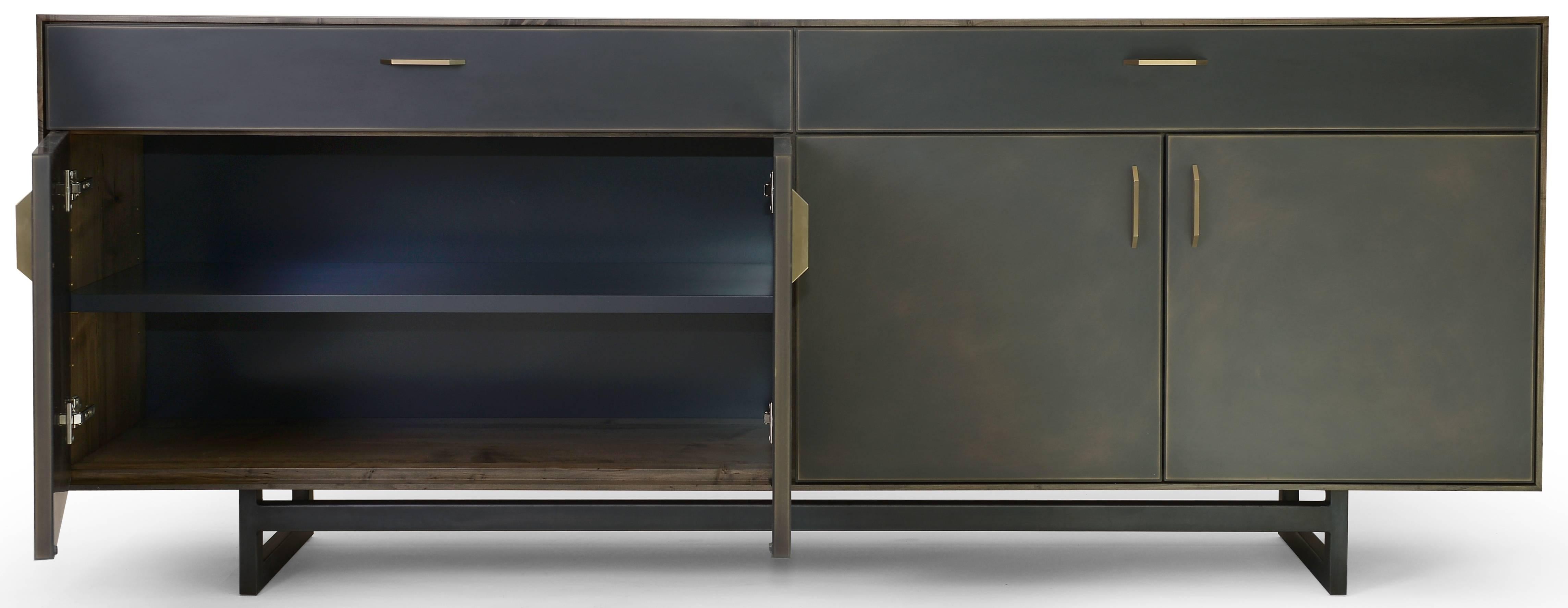 The Gotham credenza features clean lines that blend harmoniously with the beautiful mix of materials used in this collection. A delicate oxidized ambrosia maple frame sits on a blackened steel base with custom hand-sculpted bronze pulls on the