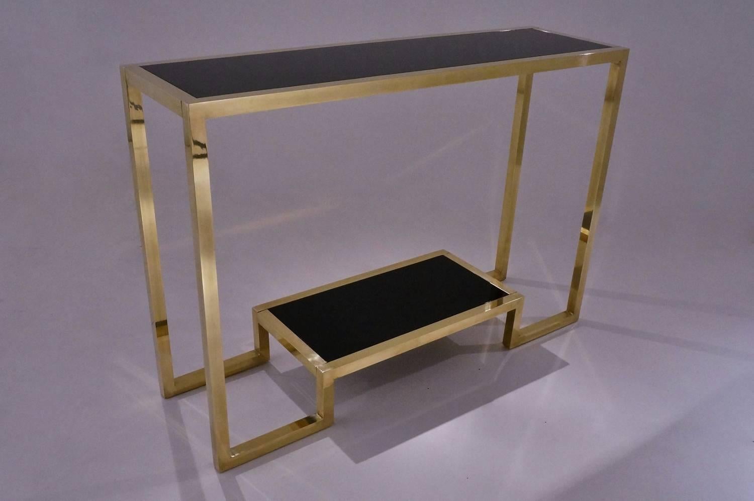 Pair of brass console tables with a black lacquer top and shelf in the style of Guy Lefevre, circa 1990s, French.

This pair of console tables have been thoroughly cleaned respecting the original patina. They are ready to use.

In this design,