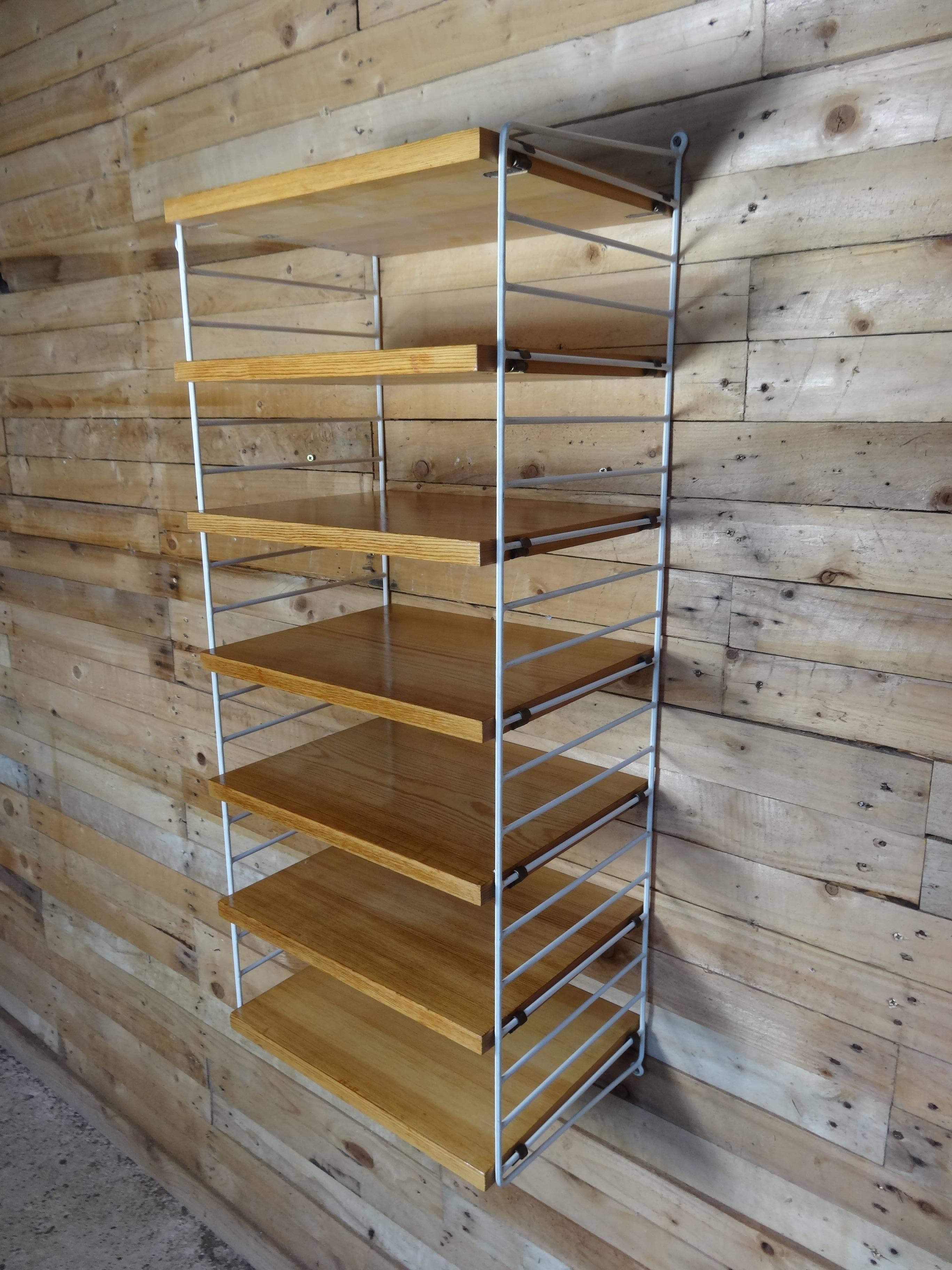 Retro 1950s tall string wall system shelving unit.

Early string wall system in very good vintage condition. The string wall system was designed in 1949. Over the years it has evolved from being a ground-breaking concept to becoming one of the