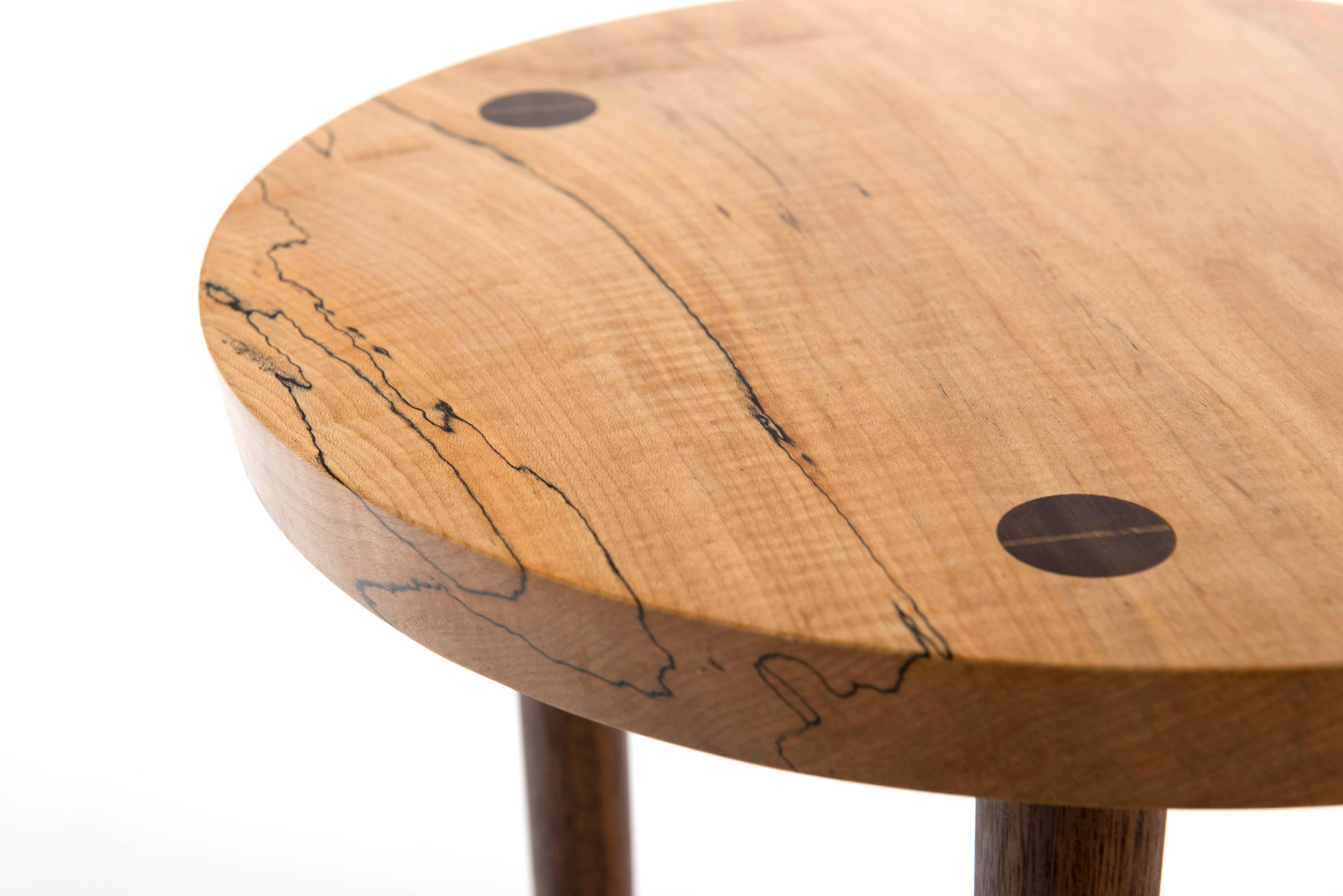 Edition of 15. This three-leg design centers around the through-cut joinery affixing the subtly beveled edge of the curly Maple top with the Black Walnut base. A graphic wedge of Maple in this joint bisects the circular face of each Walnut leg. To