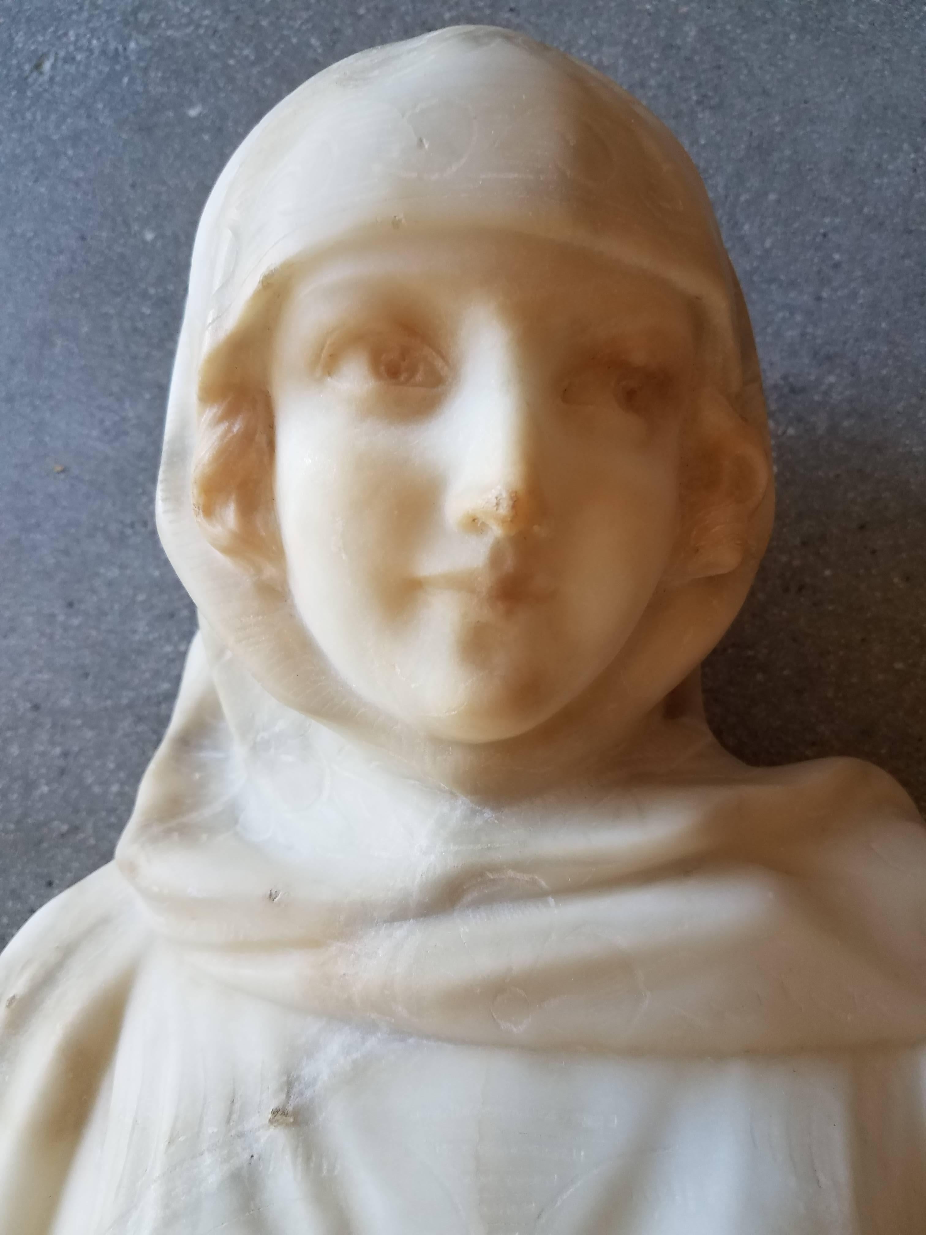 This antique marble bust has beautifully carved features and the garment has etched flowers and details of design. The piece has a beautiful presence.