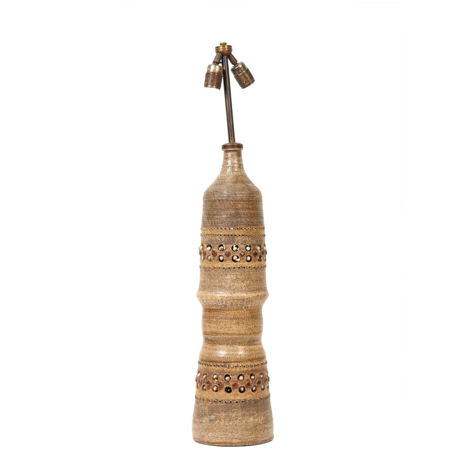 Made of ceramic with banded circular incised cut-outs and inset enameled pastilles, this mid-century Georges Pelletier lamp is a rare find. The ceramic base features a matte textured glaze in earth tones of gold and ochre. In good working condition,