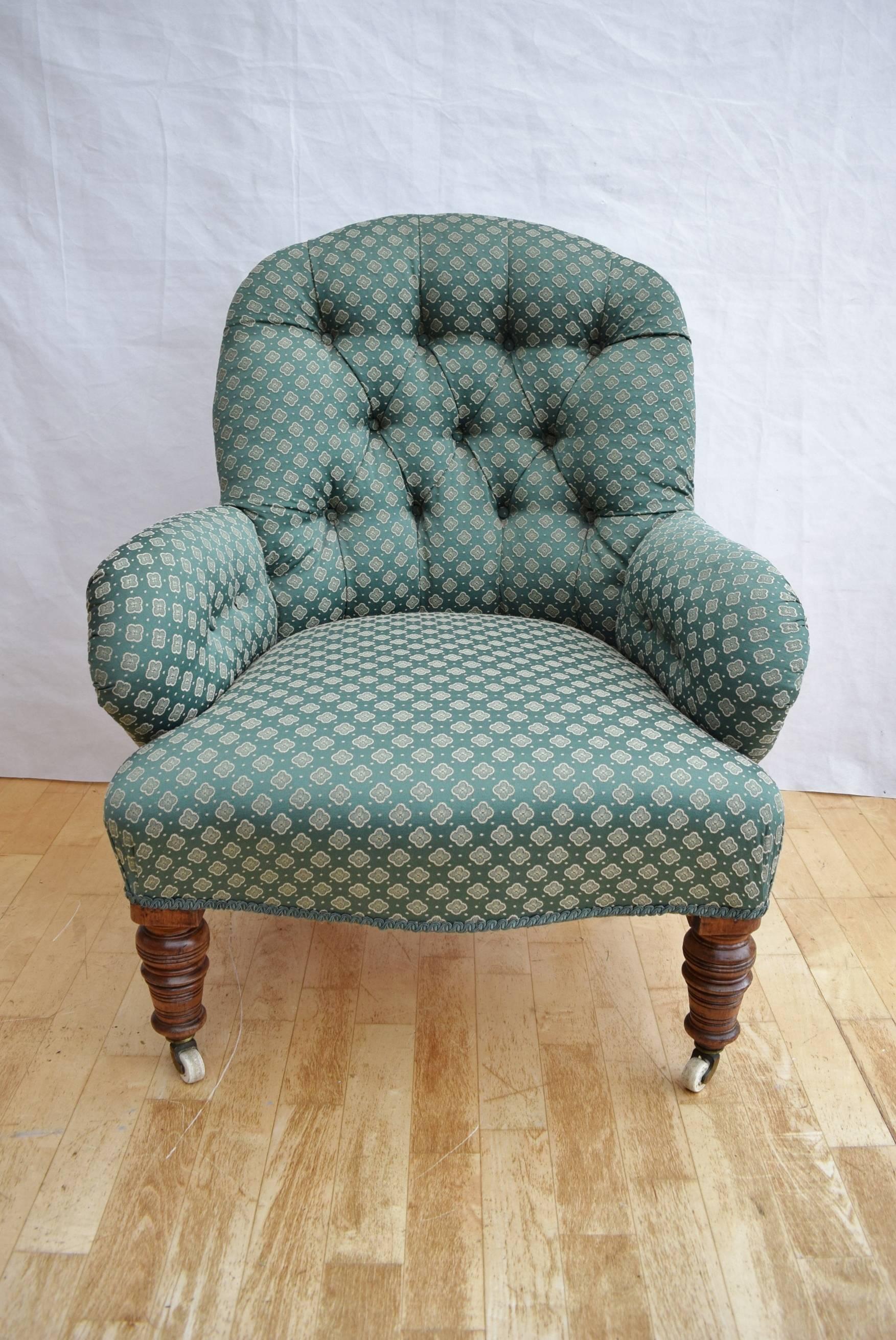 Deeply buttoned and pleated backrest leading to padded webbed and sprung fixed base

The armrests are full upholstered with buttining to the inside

The upholstery is a sea green cotton weave with green braide

The chair is raised upon walnut