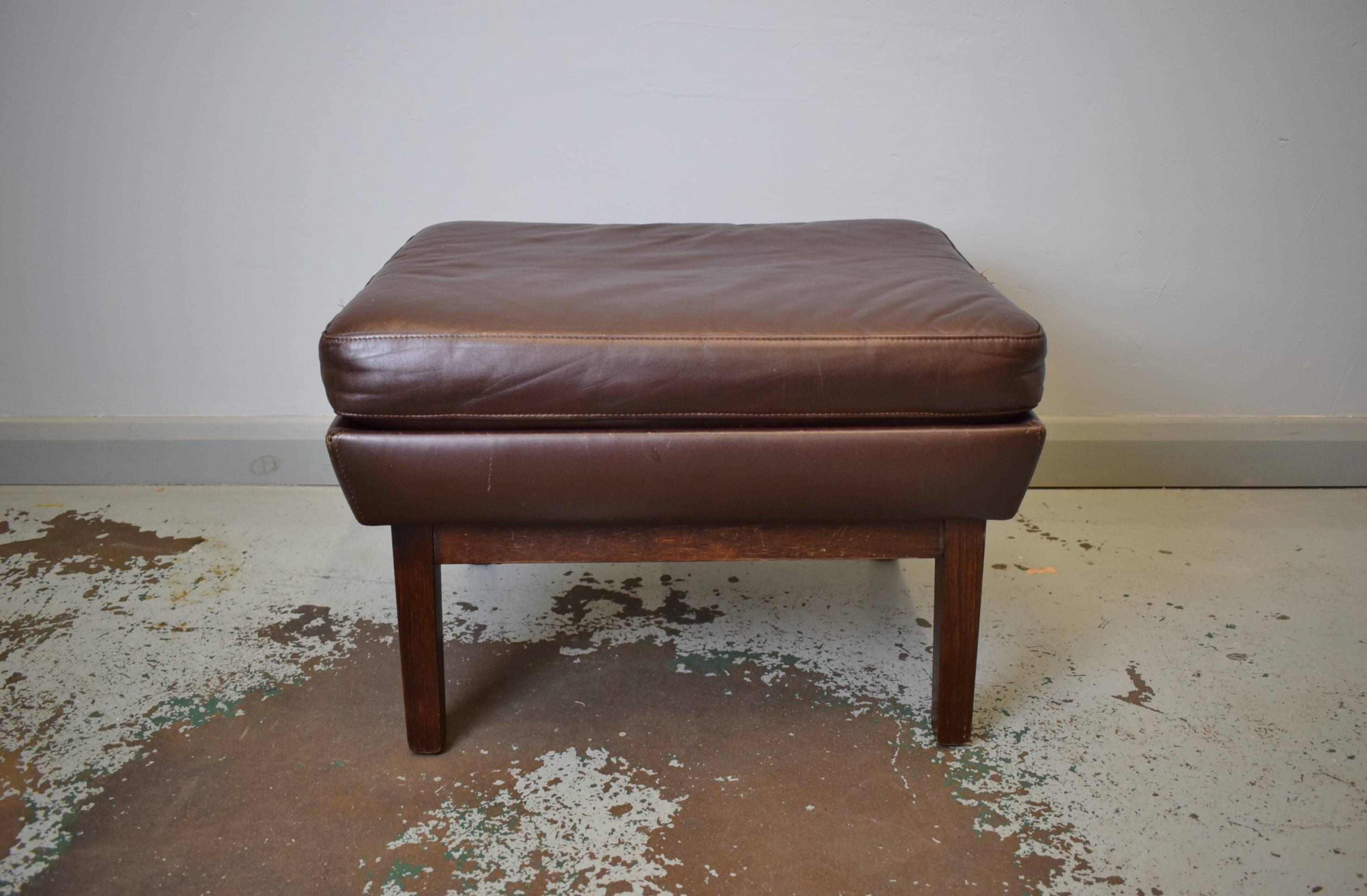 Designer: Danish

Manufacturer: Unknown

Country: Denmark

Date: 1960s

Material: Brown leather and stained beech legs.

Maximum dimensions: 57 cm wide ,46 cm deep ,40 cm tall .

Condition: Excellent with the odd scuff mark sturdy frame