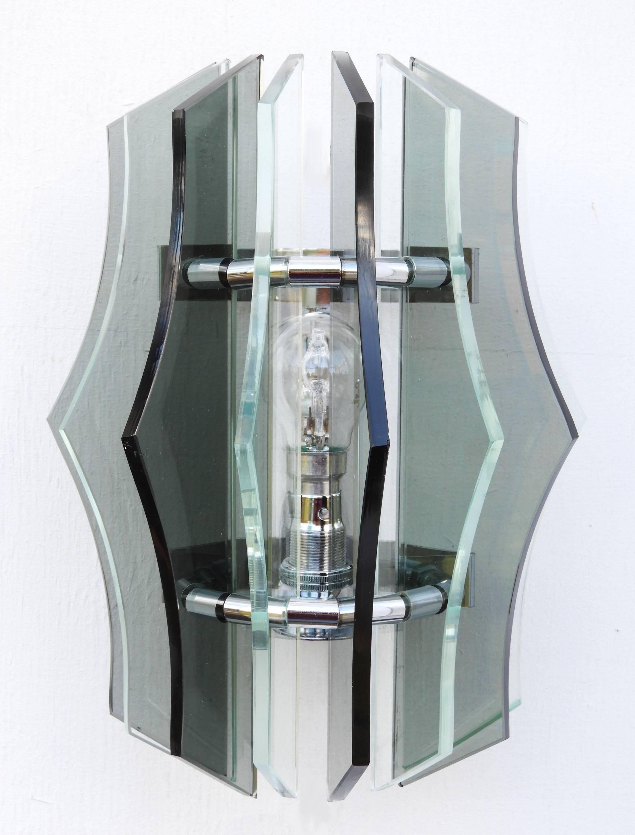 Pair of Italian midcentury smoked glass wall light sconces, circa 1970
Veca without label
Eight alternating geometric shaped clear and black smoked glass in semi circular form on a chromed frame structure.
In very good condition with only minor