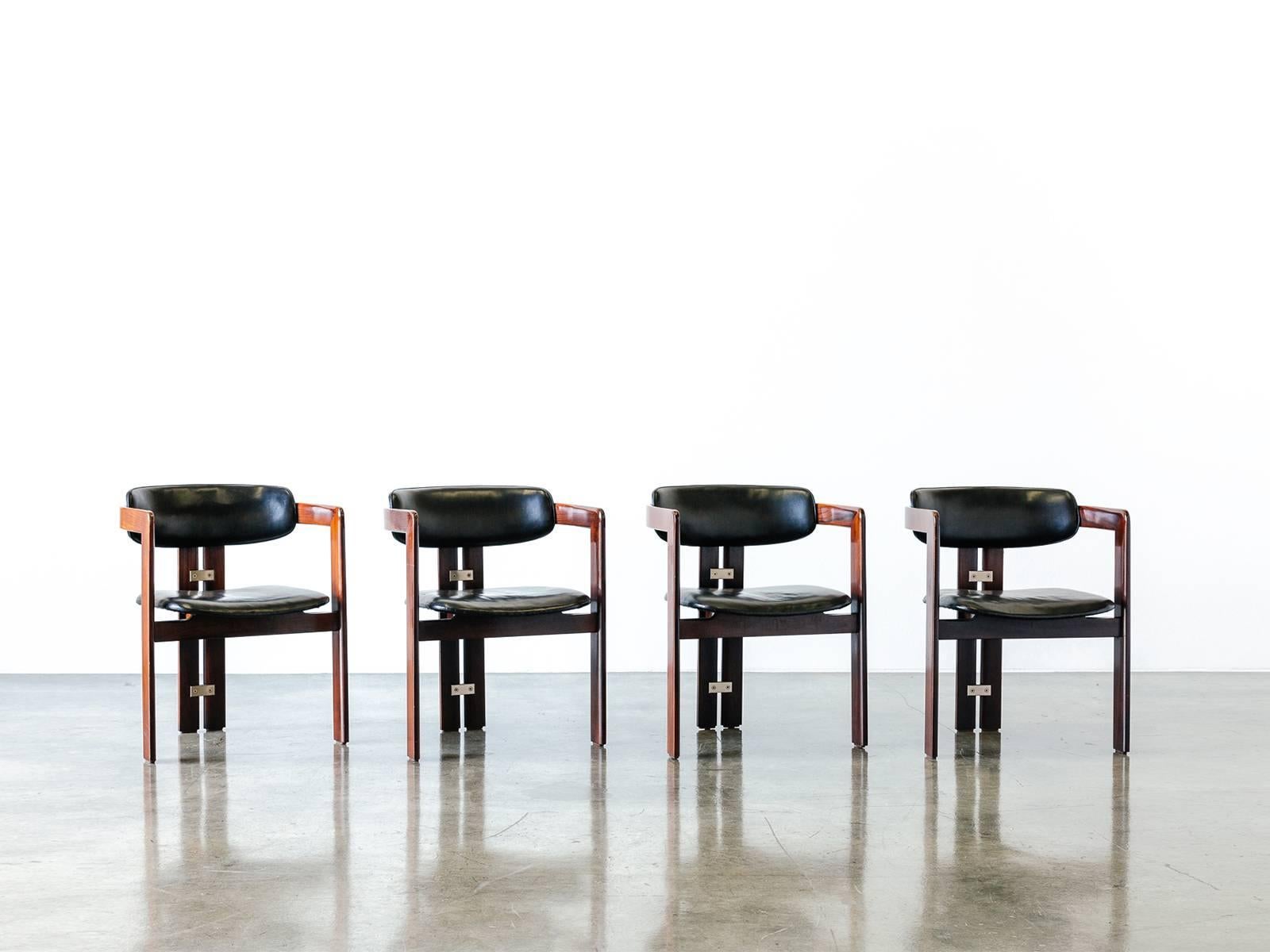 Stately set of four armchairs made from varnished solid rosewood designed by Augusto Savini for Pozzi in 1965. The arms of the chair flow around and down the back to provide structural support. Small, well-crafted aluminum fittings join the