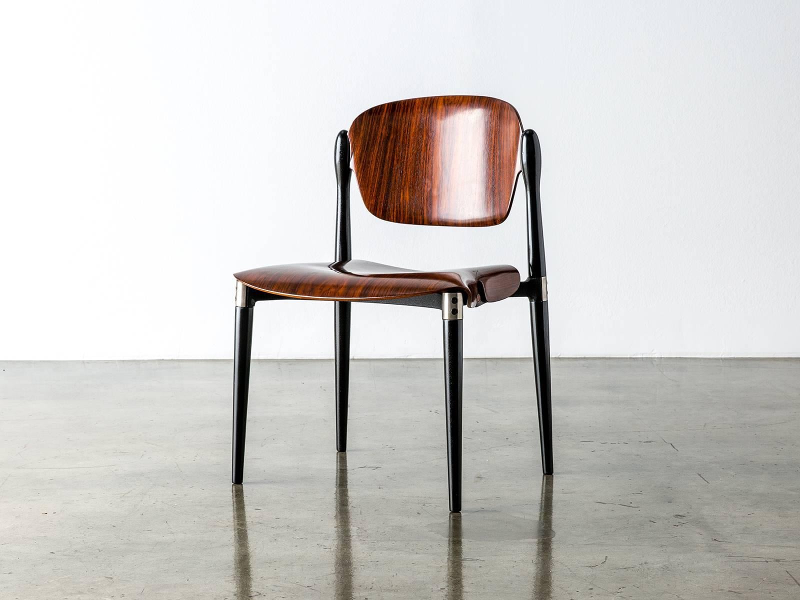 A compact and comfortable chair designed by Eugenio Gerli for Tecno in 1962 that suspends two molded rosewood panels to simple and elegant effect. Black lacquered legs are joined by a die-cast aluminum underside support and aluminum fittings. The