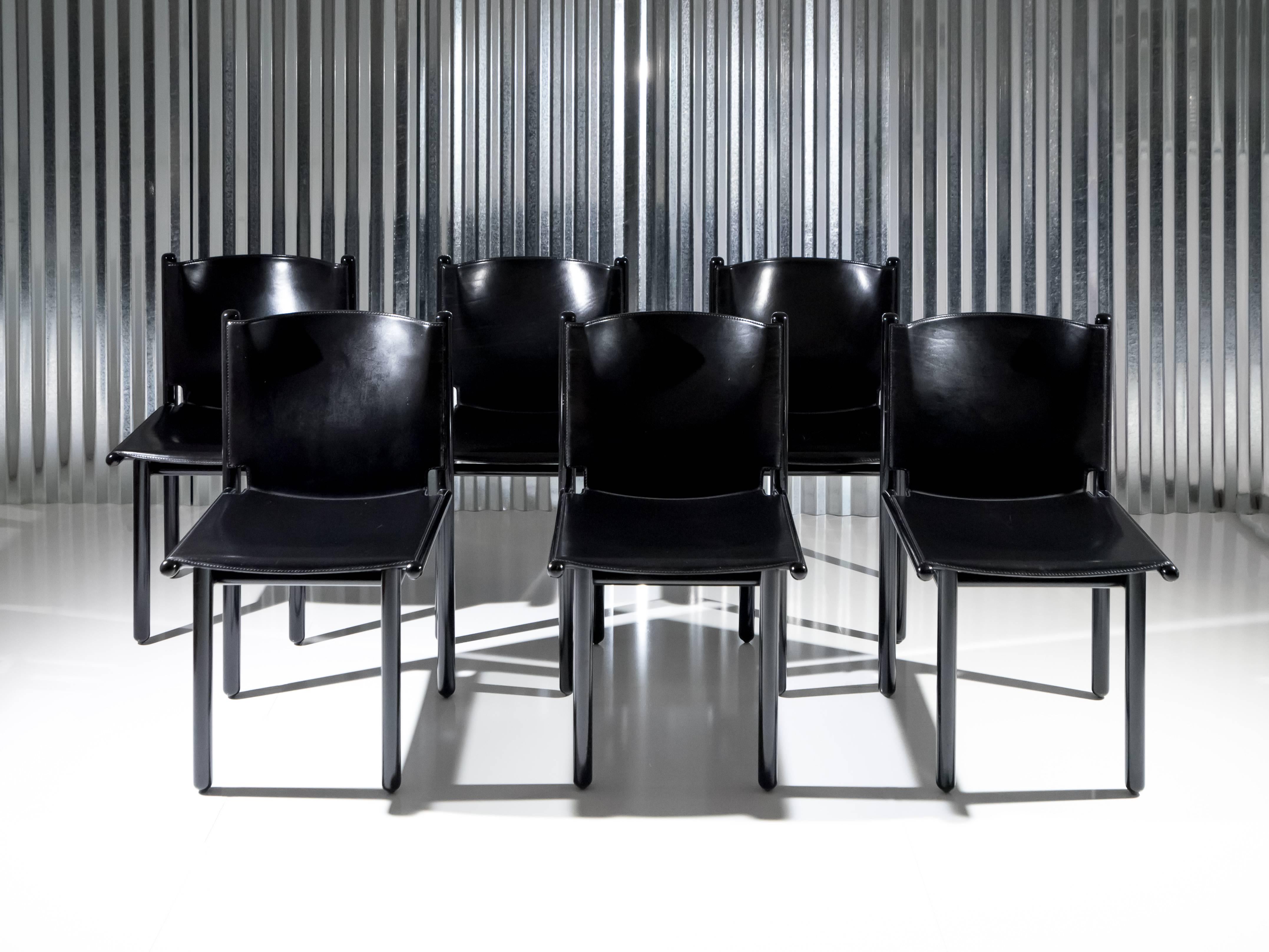 This set of six 'Caprile' chairs designed by Gianfranco Frattini for Cassina in 1985 display a black lacquer finish that elegantly merges with the black saddle leather molded seat and back. Designed by Frattini after spending the previous year in