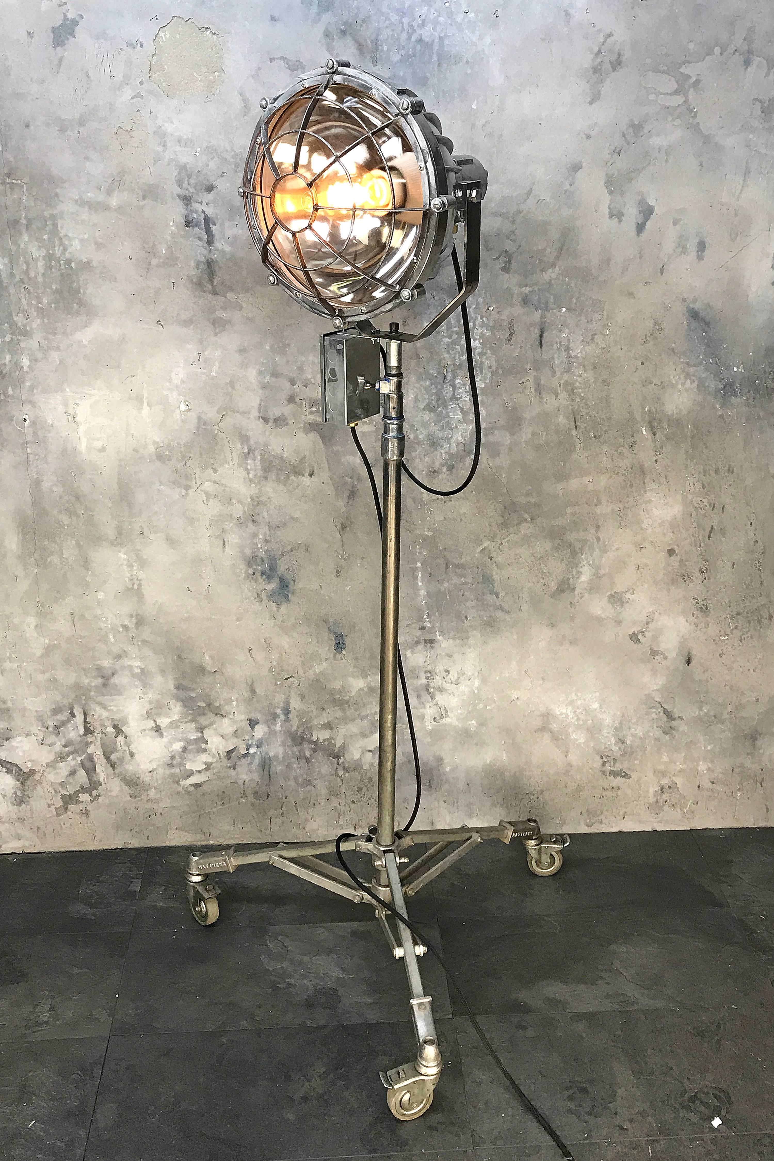 Reclaimed Japanese explosion proof spot light and Matthews theatre tripod. 

The lamp is aluminium cast with fins for cooling with convex glass, which creates a wider beam and is protected by a bulls eye style cage which is made from steel