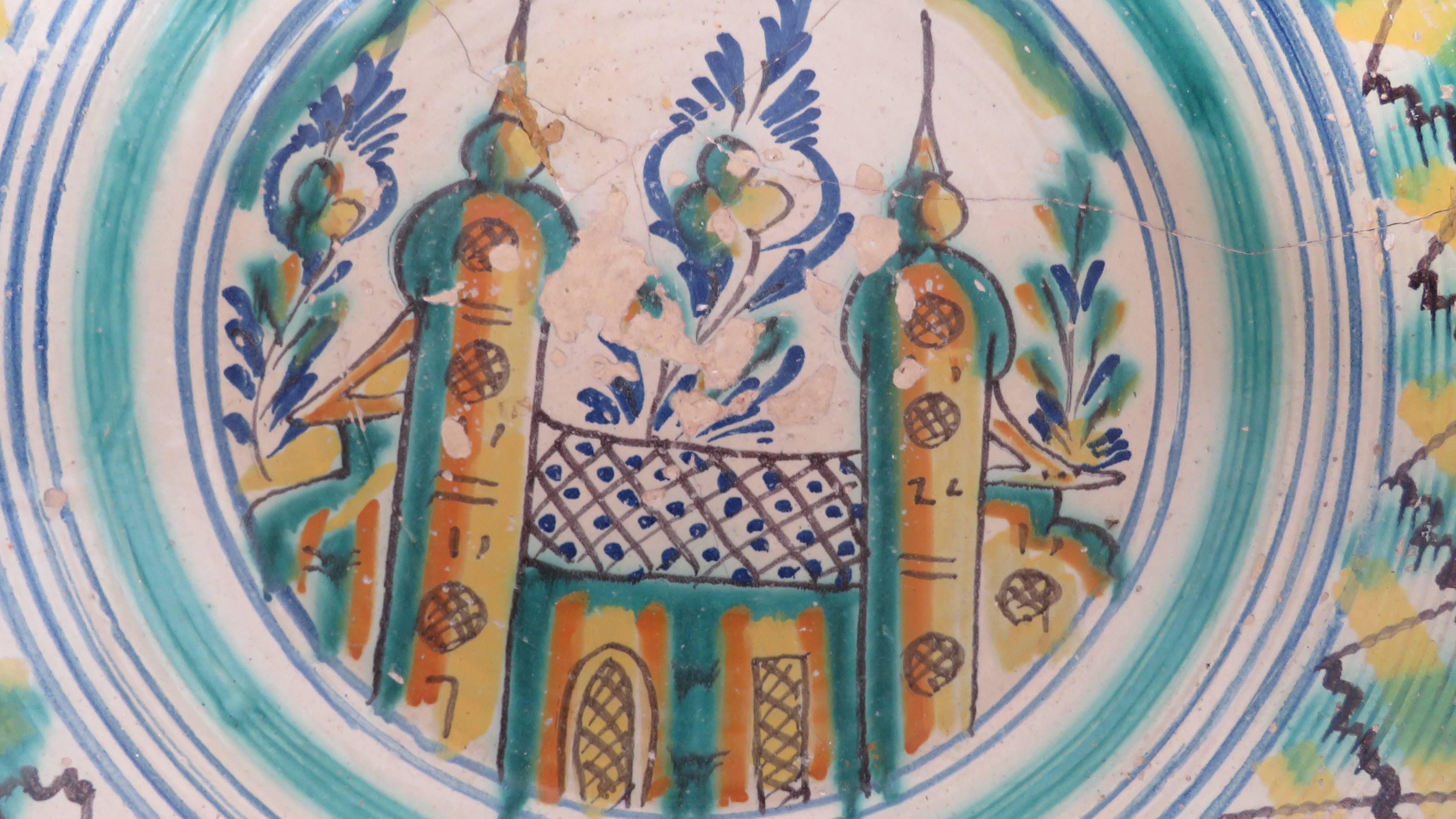 Glazes of copper green, cobalt blue, yellow and manganese on a bone white slip with a castle within a landscape setting of flowers. Origin: Sevilla, Spain

Back metal hooks included.