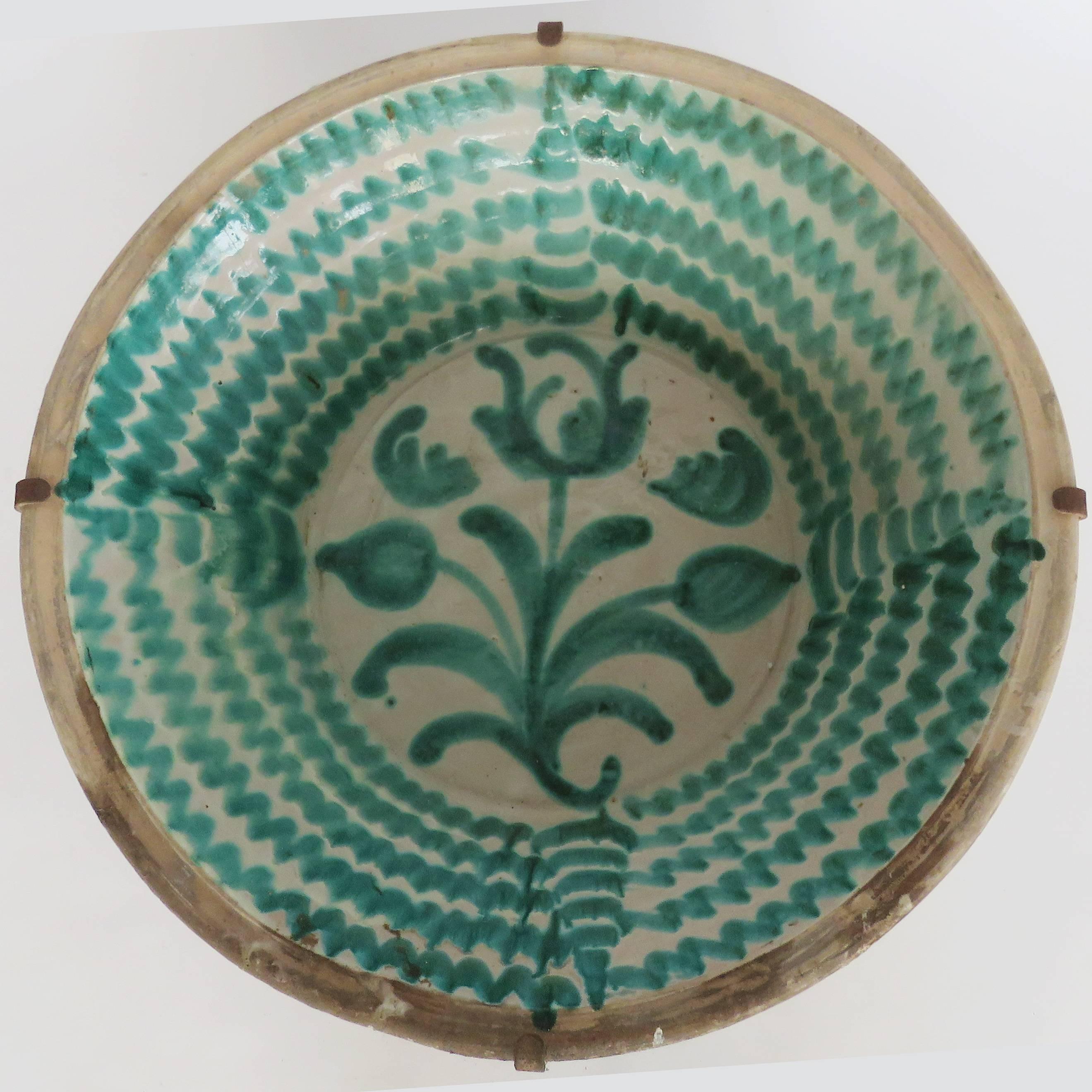 Deep green glaze over a milky white slip featuring a large blossoming flower surrounded by whimsical foliate motifs. Origin: Granada, Spain.

Back iron hooks included.