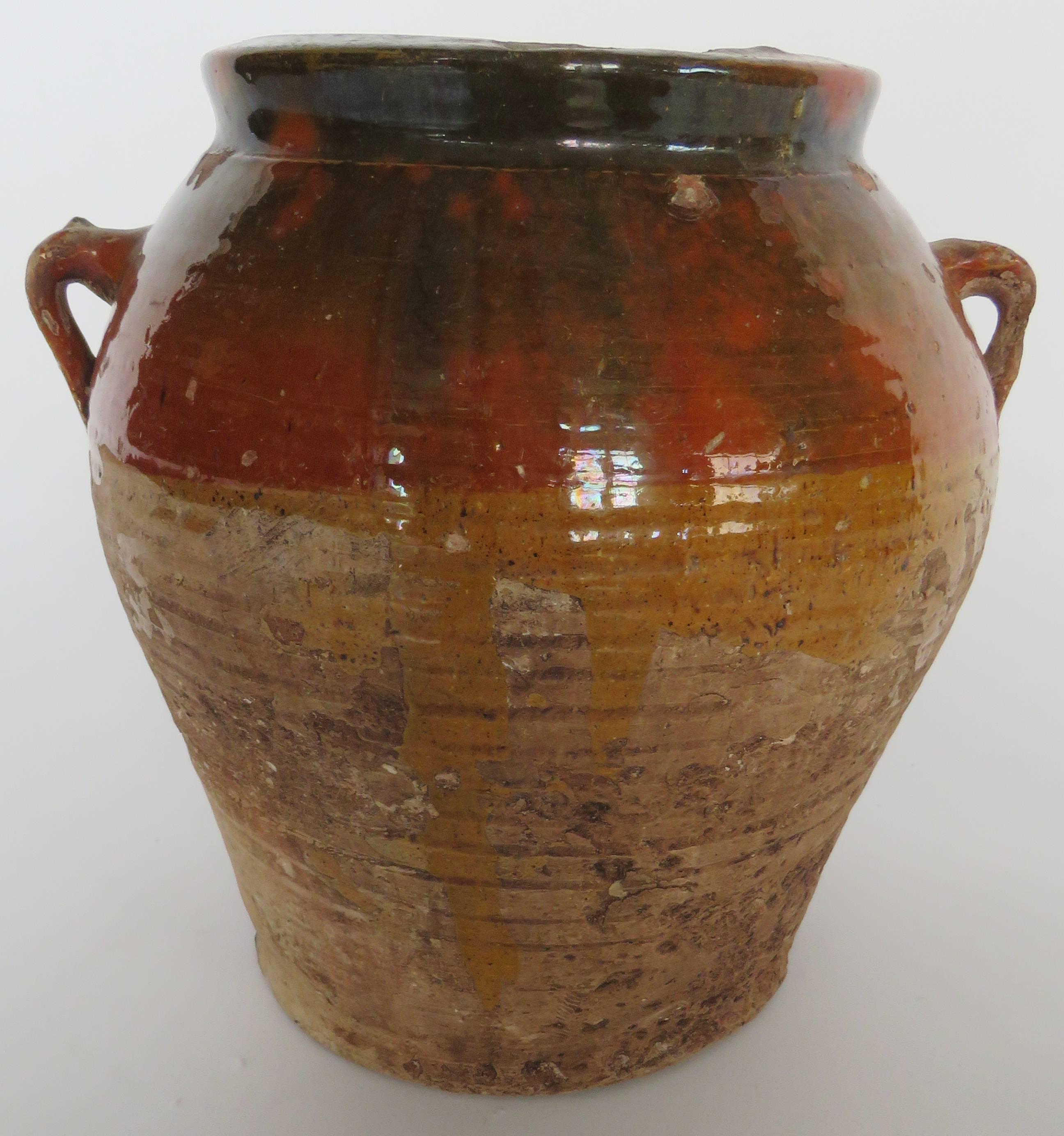 Hand coiled ribbed pot with two handles decorated with forest green, rust orange and mustard yellow drippy glaze around neck.

Shipping costs per item diminish with purchases of additional items. 
Photo of collection of pots it is to show more