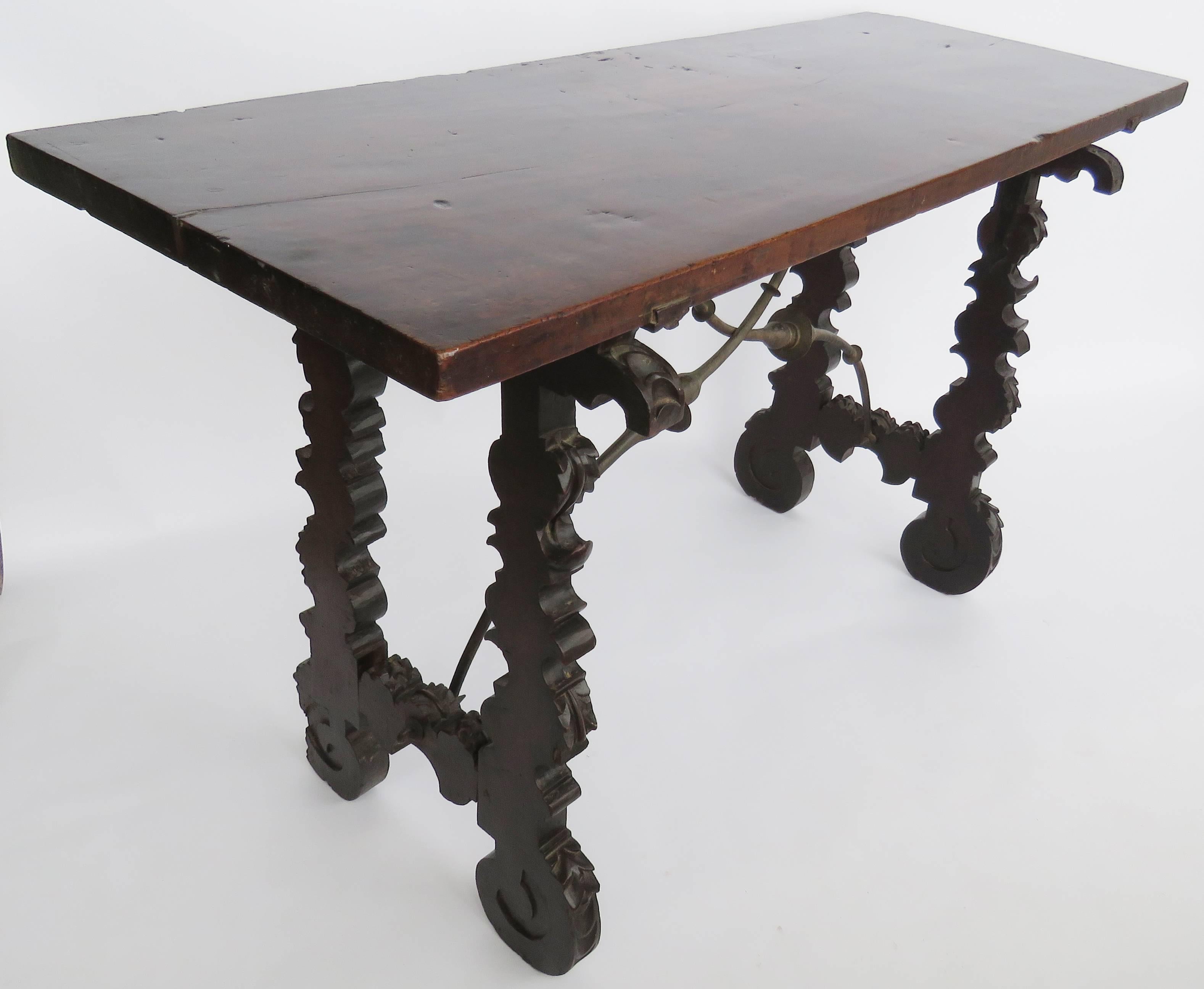 Rectangular single plank top over removable acanthus supports raised on molded elaborately chip-carved scrolled legs ending in inward scrolling feet, united by similar stretchers, joined by forged iron incurving supports. Folding table for travel