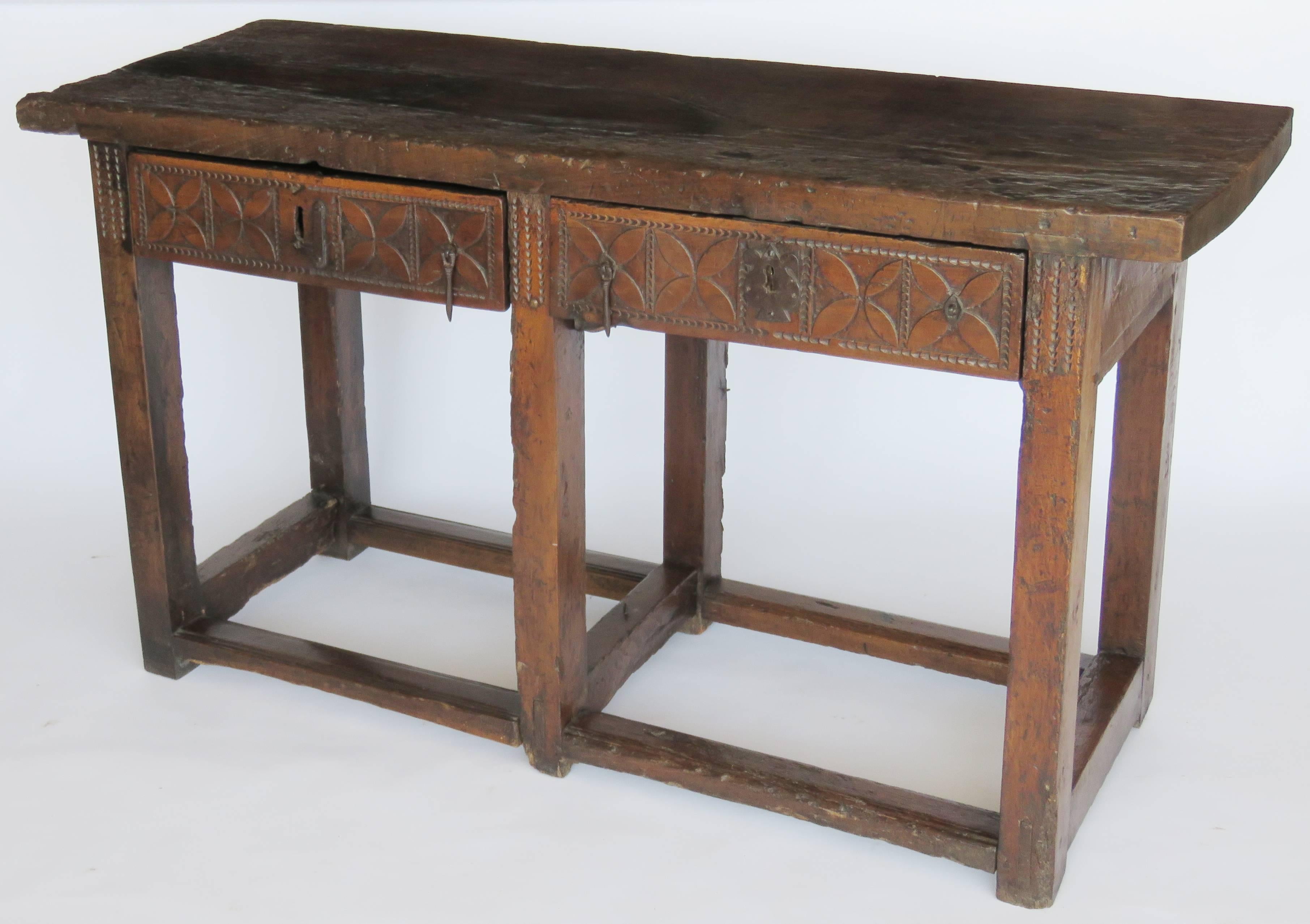 Rectangular top above two drawers with geometric carved panels raised on square form legs joined by perimeter stretcher.