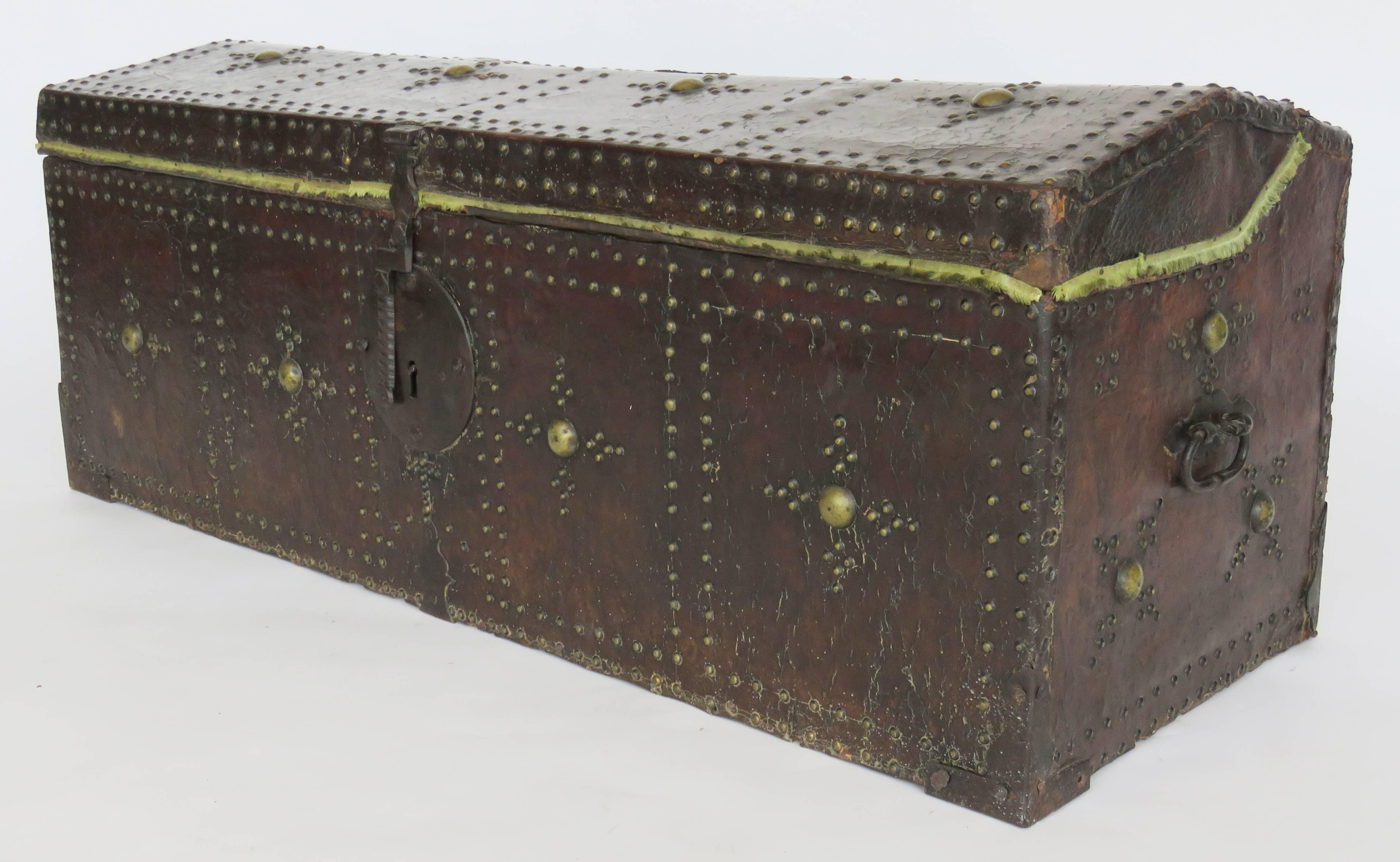 The hinged dome lid over a conforming rectangular case fitted with an iron lock plate and decorated overall with brass nailhead pattern in four quadrangles.