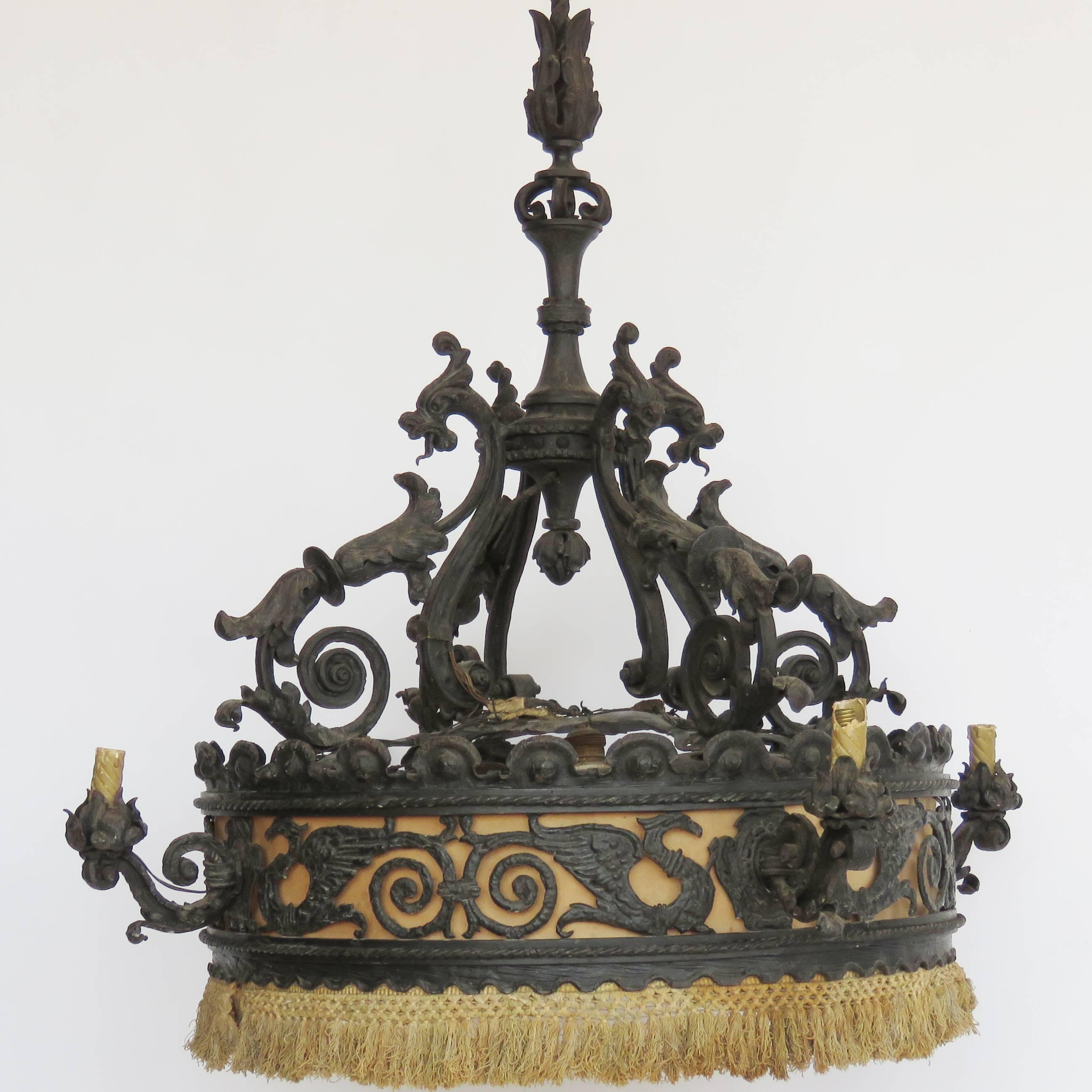 Hammered iron chandelier of Gothic influence. Lined with lighter colored fabric to show off the intricate detail of the ironwork with scrolls, griffens and dragons. Four outer lights, five inner lights.

Provenance: Barcelona, Spain.

Chandelier