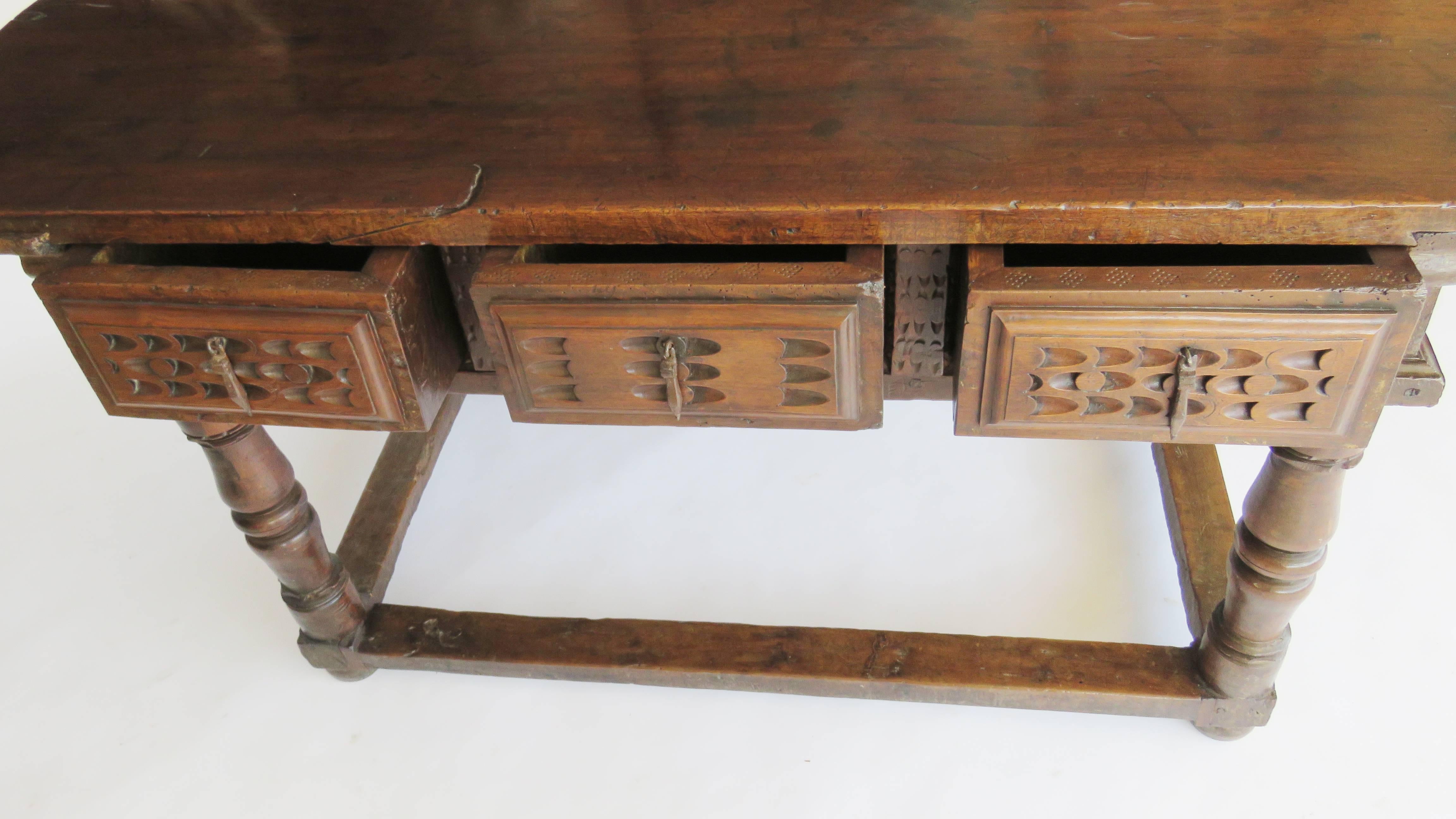 Rectangular single plank top above a frieze fitted with three chip carved drawers, sides and back similarly carved, raised on baluster turned legs joined by flat rectangular perimeter stretcher on compressed bun feet.

Original. Exceptional age