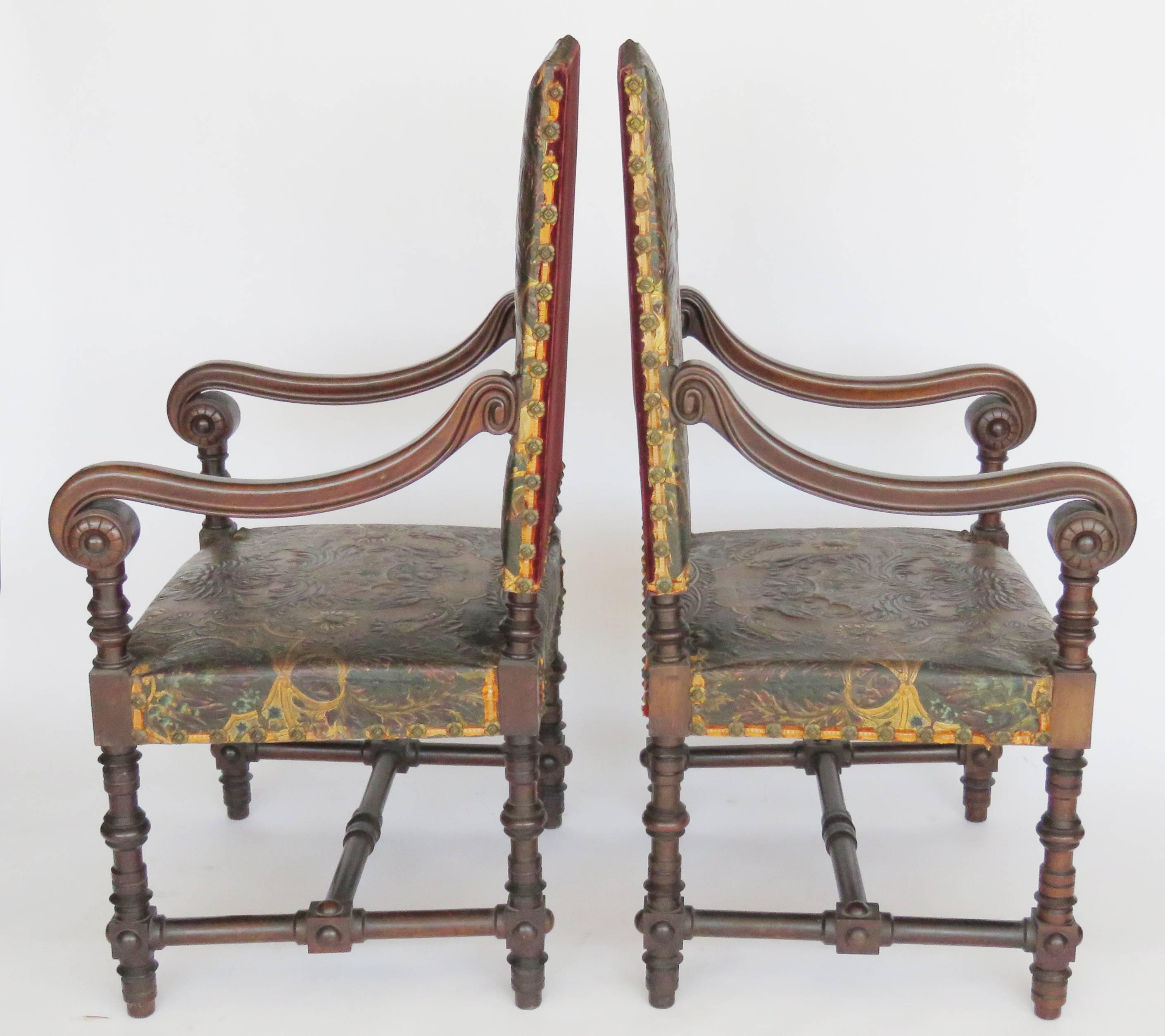 Rectangular Guadameci gilt and green tooled leather backrests with extensive decoration of foliage and parrakeets, similar seats mounted with brass buttons, downward curving armrests ending in incurving scrolls raised on baluster turned legs joined